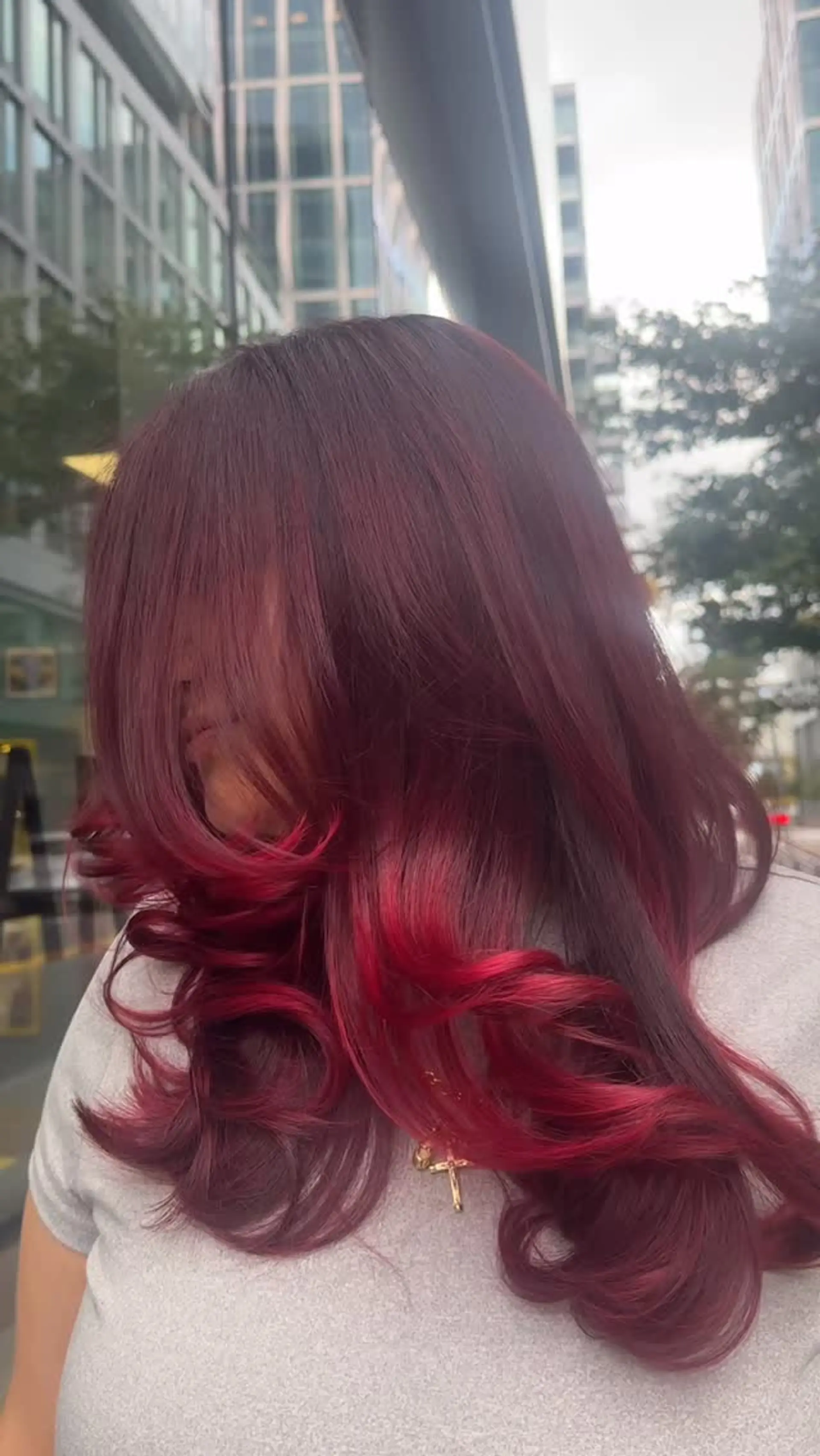 Rich berry-red locks styled smooth with voluminous face-framing layers and soft, bouncy curls at the ends. 1