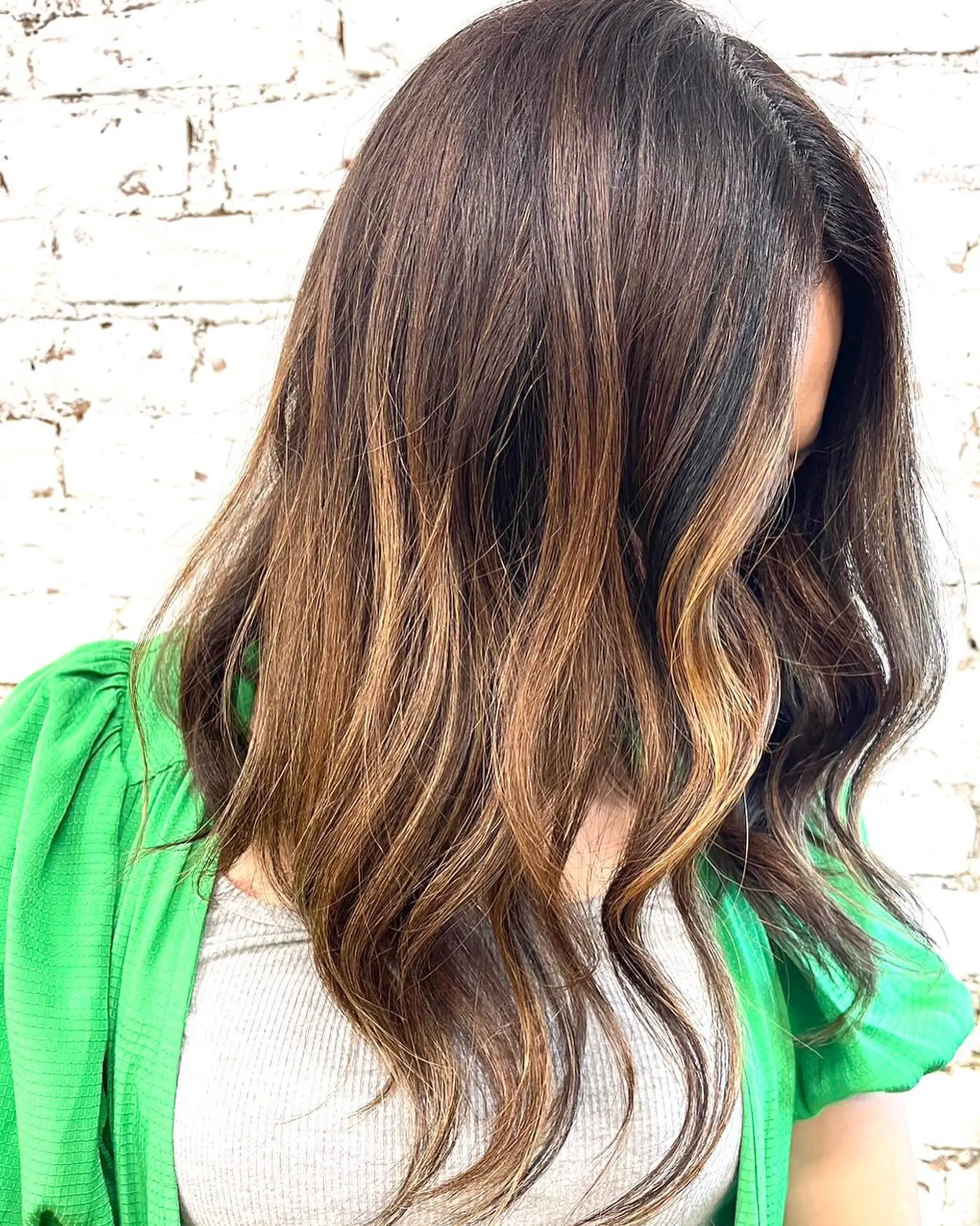 Long dark brown hair with dimensional caramel balayage highlights styled in loose, soft waves. 1