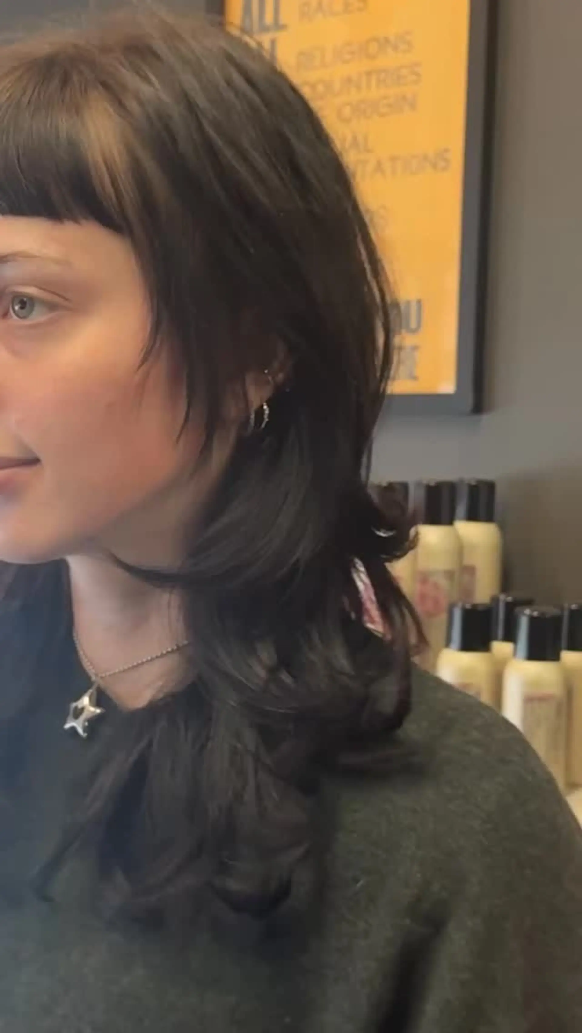 A textured mid-length layered cut featuring short graphic micro bangs and soft, outward-flipped ends. 1