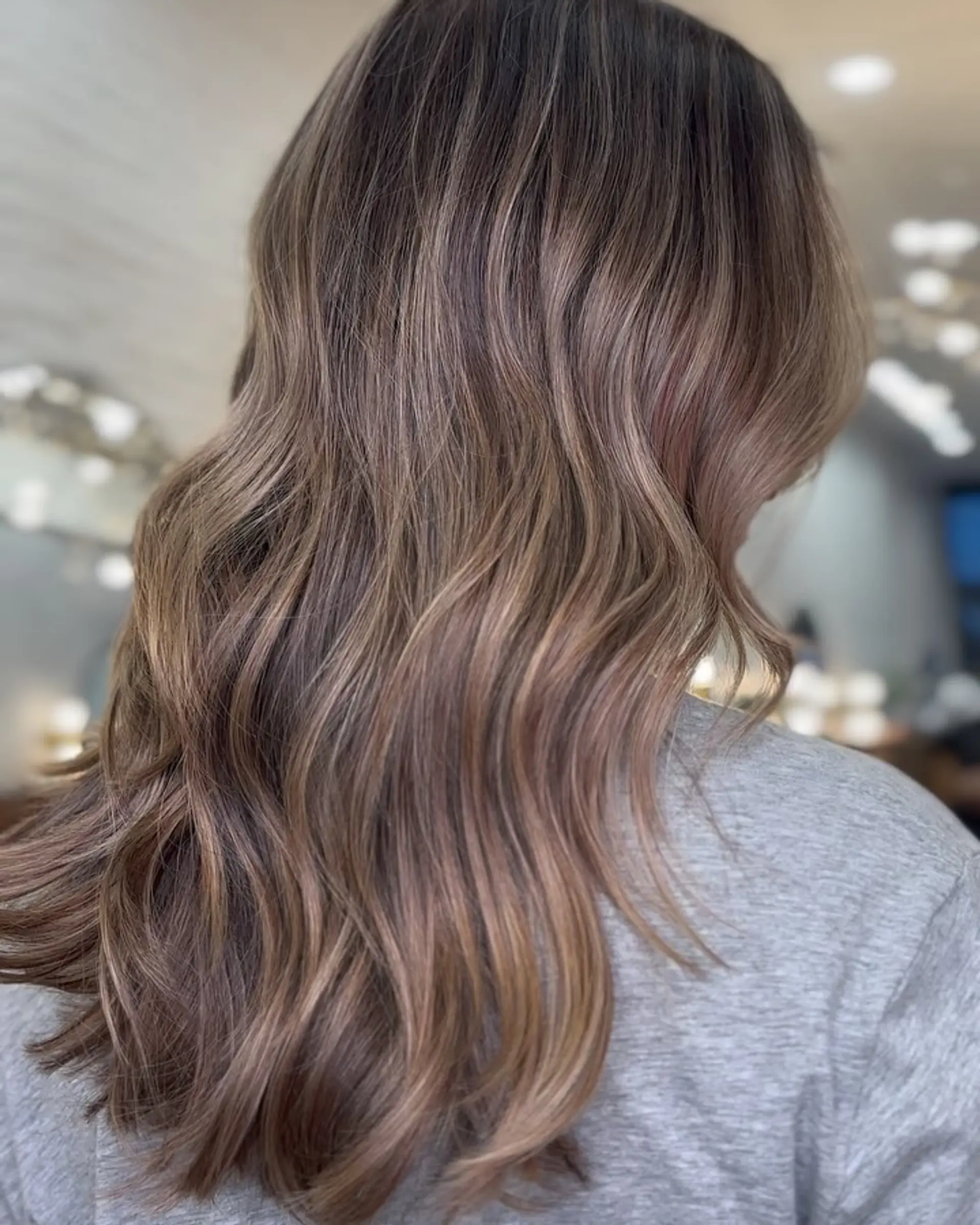 Long hair colored in a seamless, dimensional bronde shade with soft, flowing waves. 1