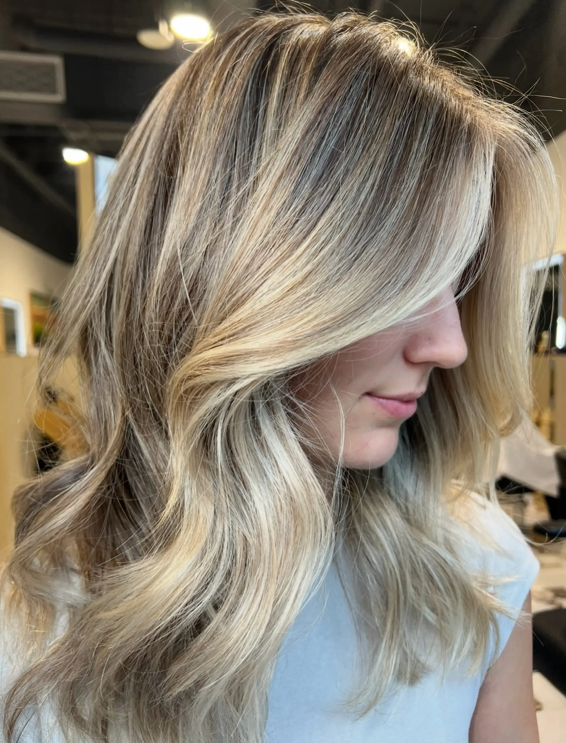 Medium-length dimensional blonde hair cut with flowing layers and styled in soft, face-framing blowout waves. 1