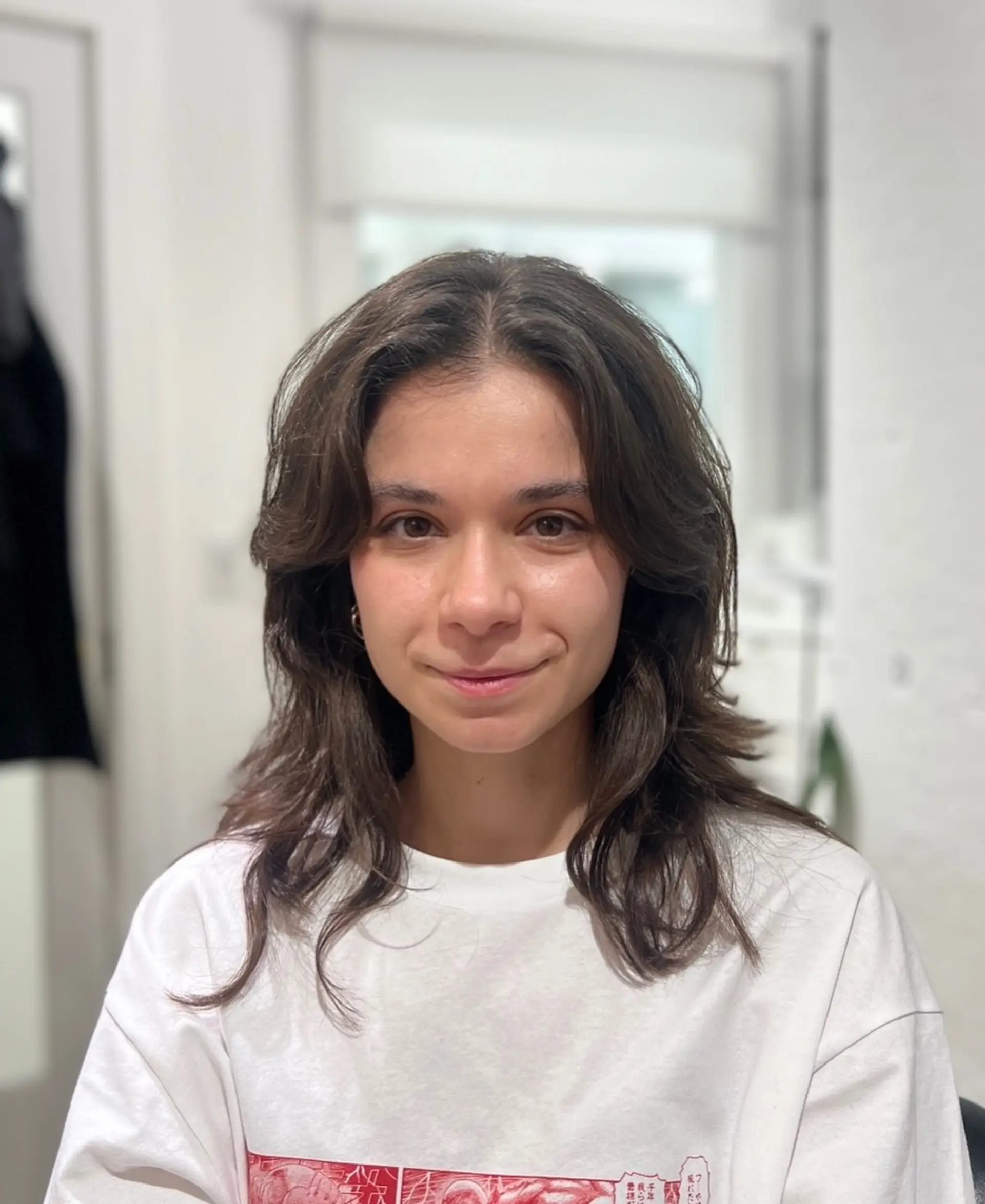 A medium-length layered haircut featuring soft curtain bangs and textured, face-framing waves. 1