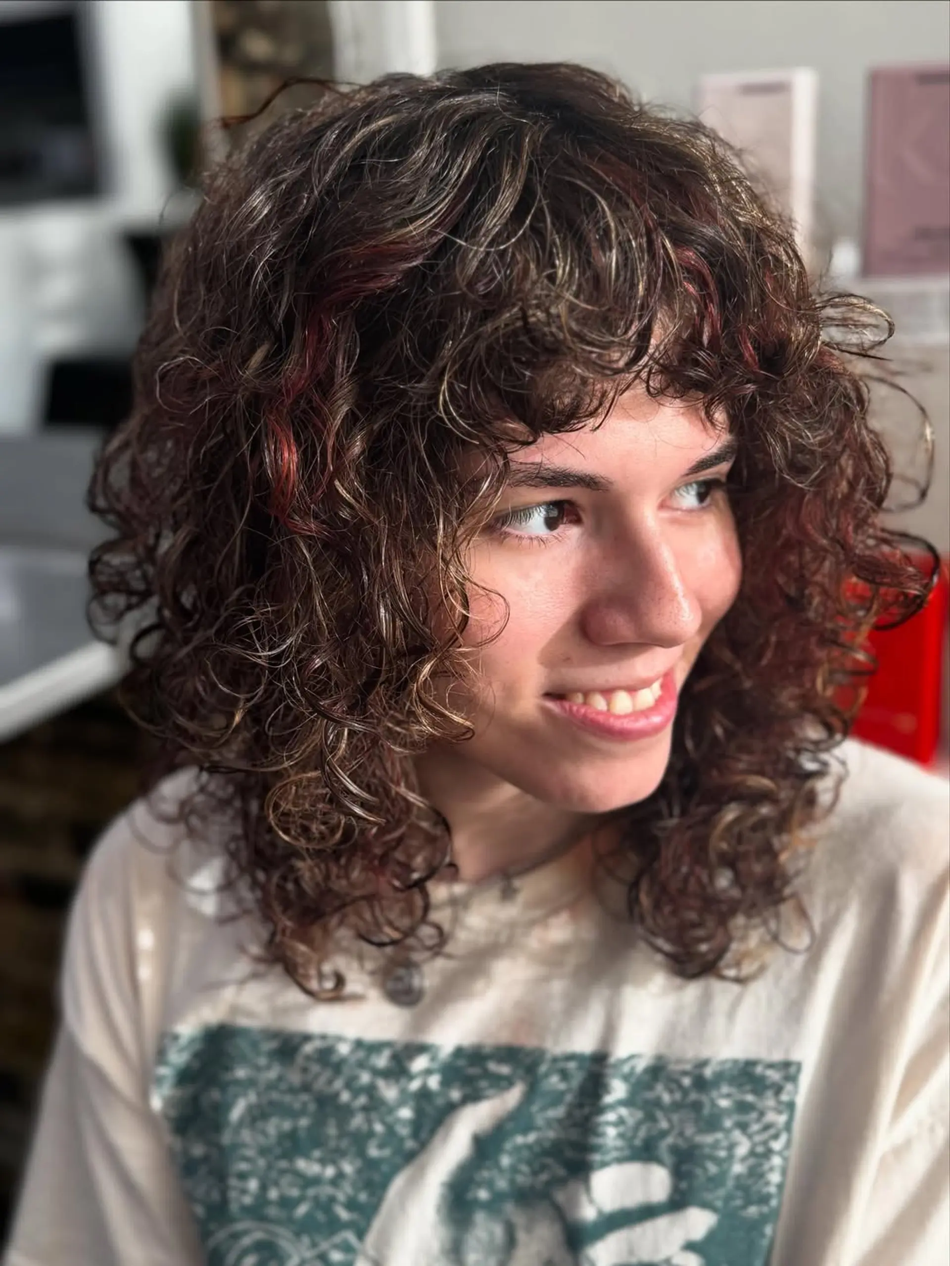 A trendy medium-length curly shag mullet haircut featuring heavy layering, short curly bangs, and a textured, voluminous finish that enhances the natural curl pattern. 1