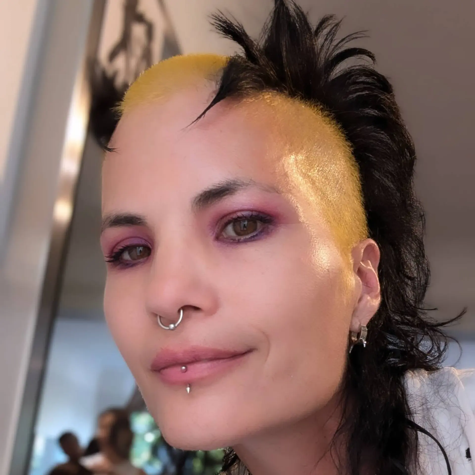 An edgy, punk-inspired style featuring close-cropped yellow sides and front, contrasted with textured, spiky black hair along the crest and nape. 1