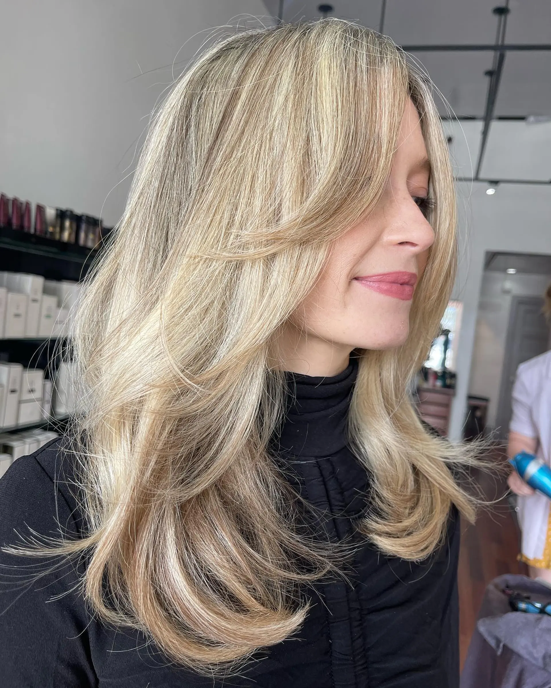 Long dimensional blonde hair styled with bouncy butterfly layers and face-framing fringe. 1