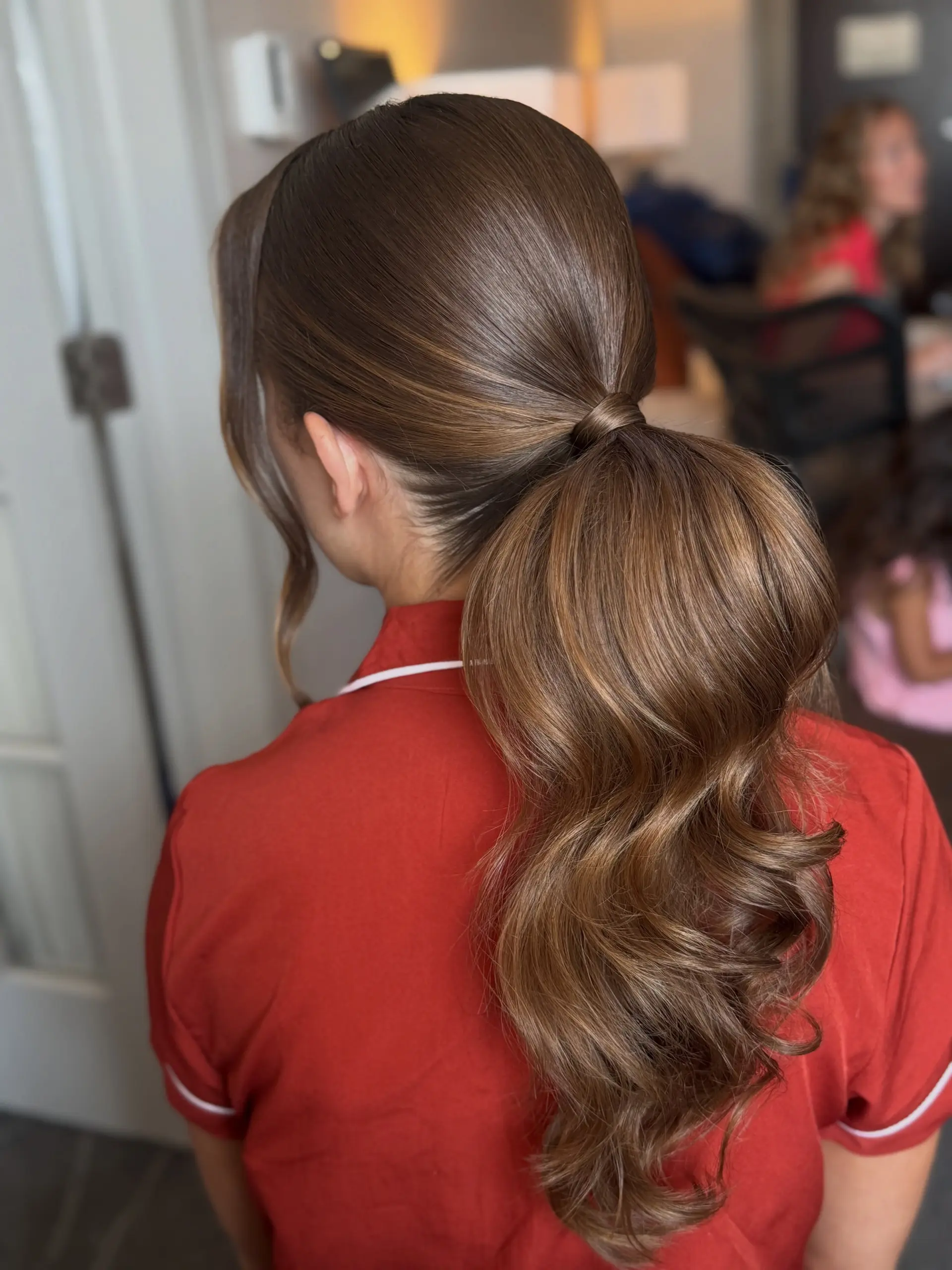 A sleek, polished low-to-mid ponytail wrapped at the base with hair and styled with voluminous, bouncy waves. 1