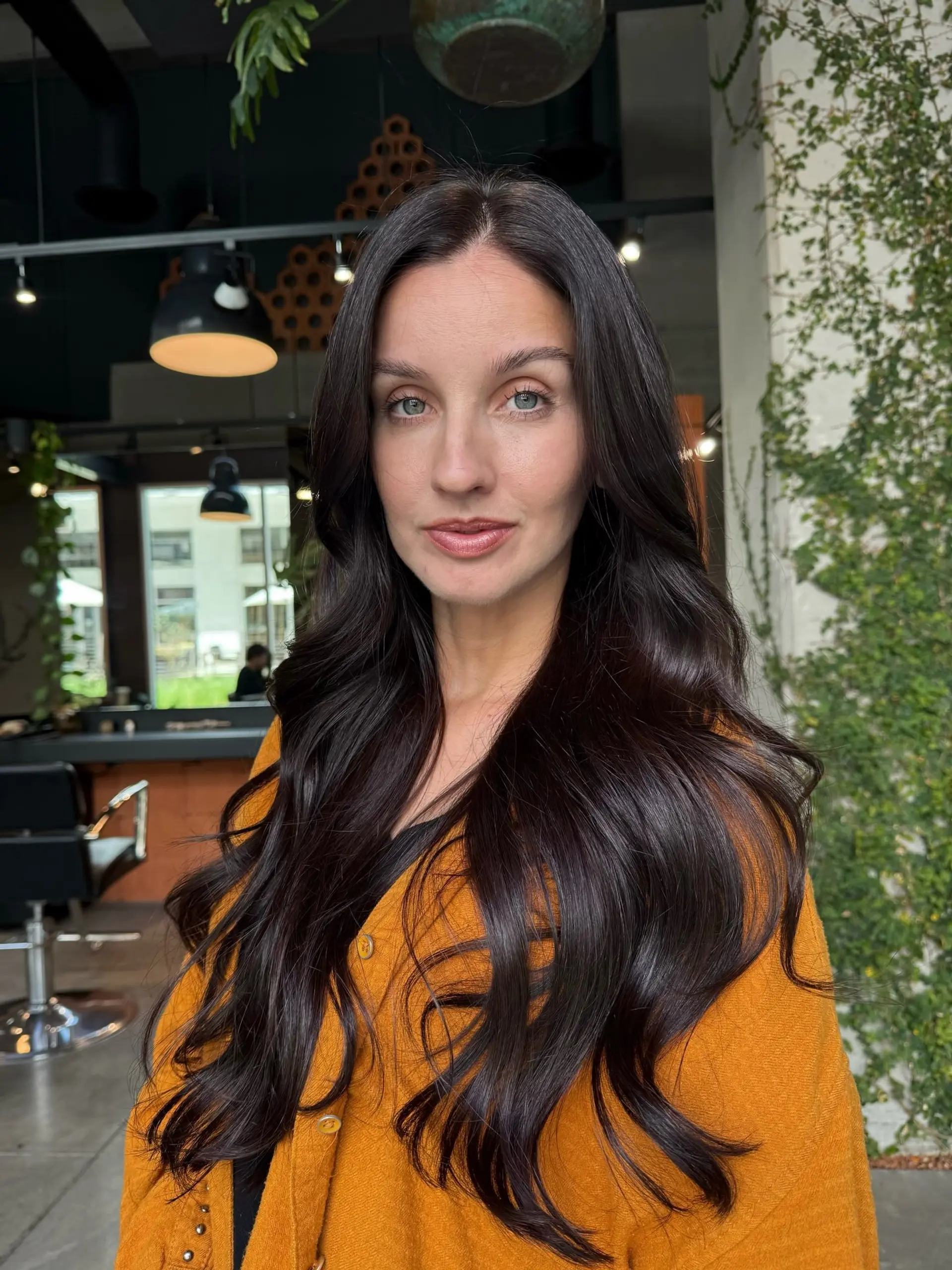 Rich, glossy dark espresso brown hair styled in soft voluminous waves with a sleek center part. 1