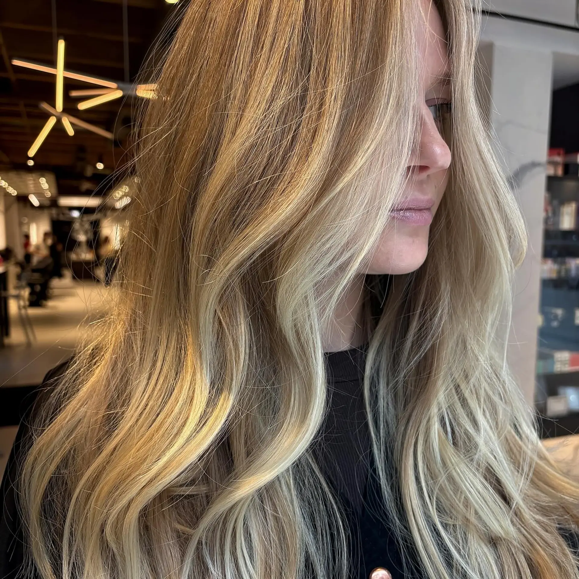 Long golden blonde hair featuring seamless dimensional highlights and styled into effortless, soft waves. 1