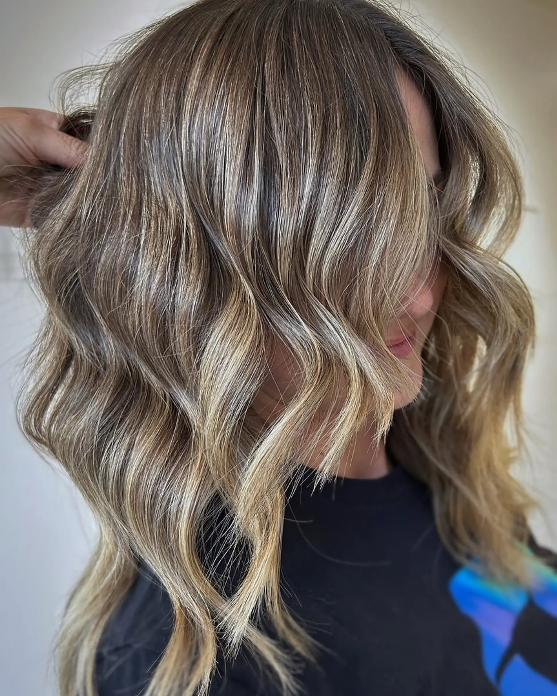 Medium-length dimensional blonde hair styled in soft, textured waves with bright woven highlights. 1