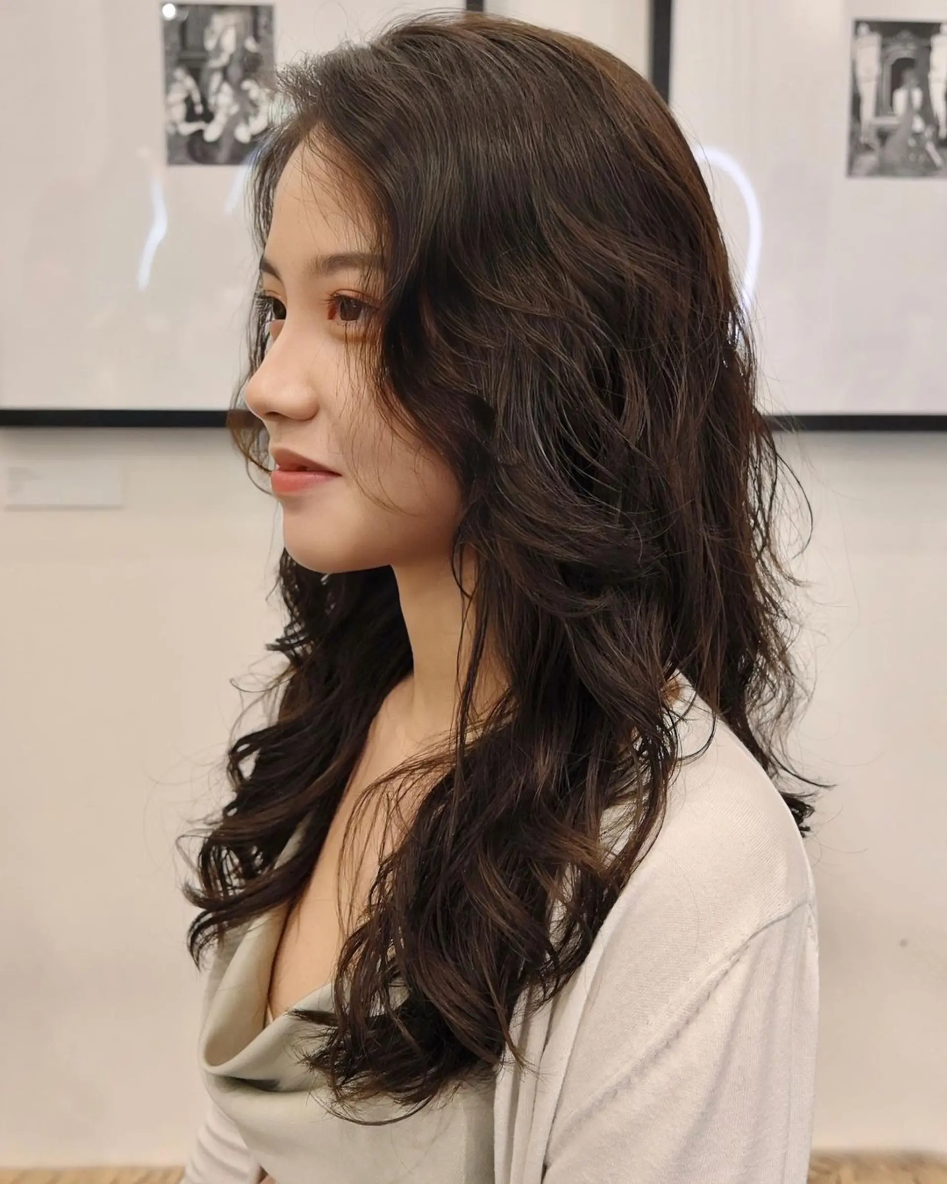 Long, dark brown hair cascades in soft, wavy layers with voluminous locks and side-swept bangs. 👩🏻‍🦱Hair by @hiro.nonstop 👩🏻‍🦱 1