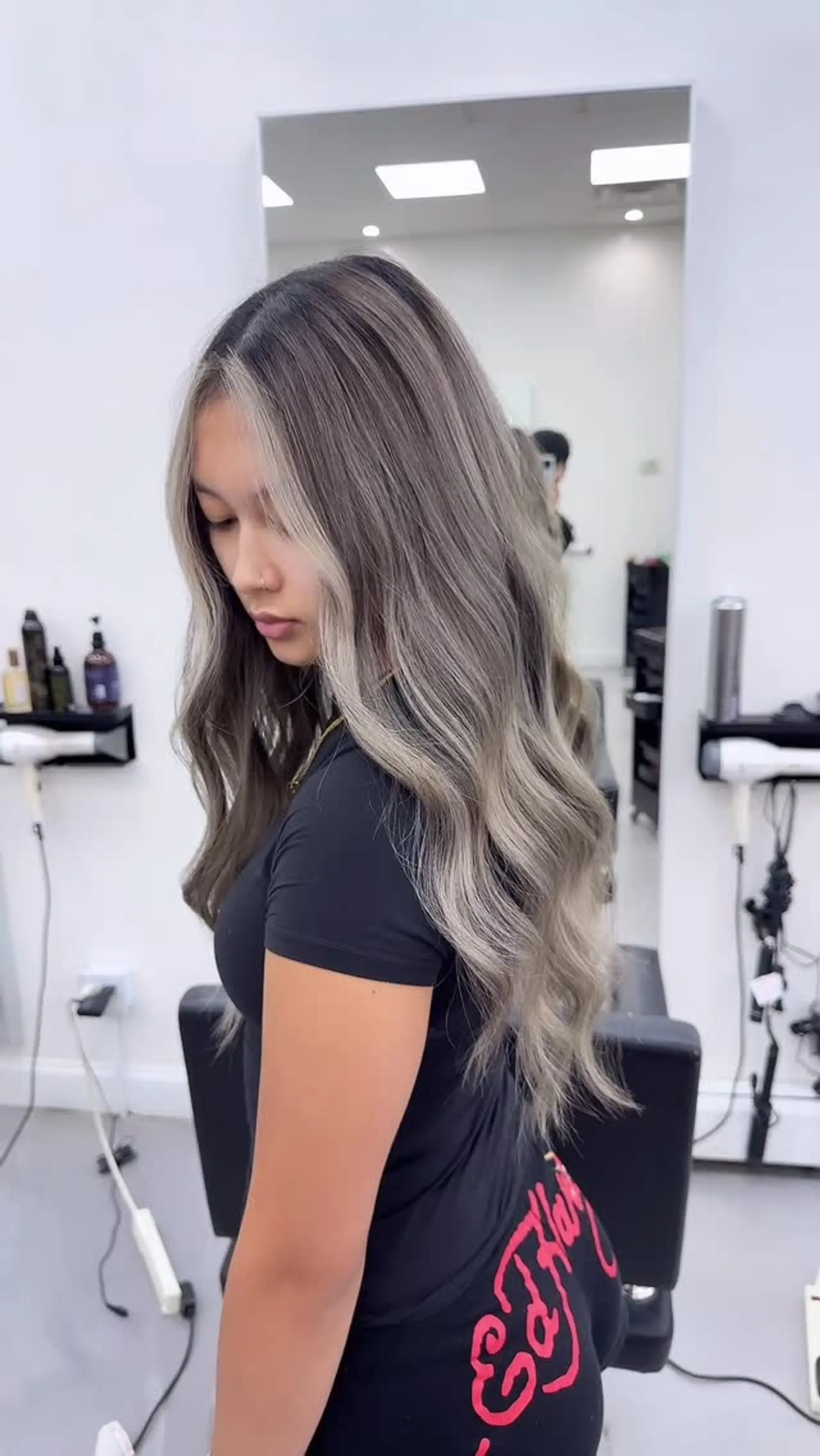 Long wavy hair featuring a seamless cool-toned ash gray balayage and a striking face-framing money piece. 1