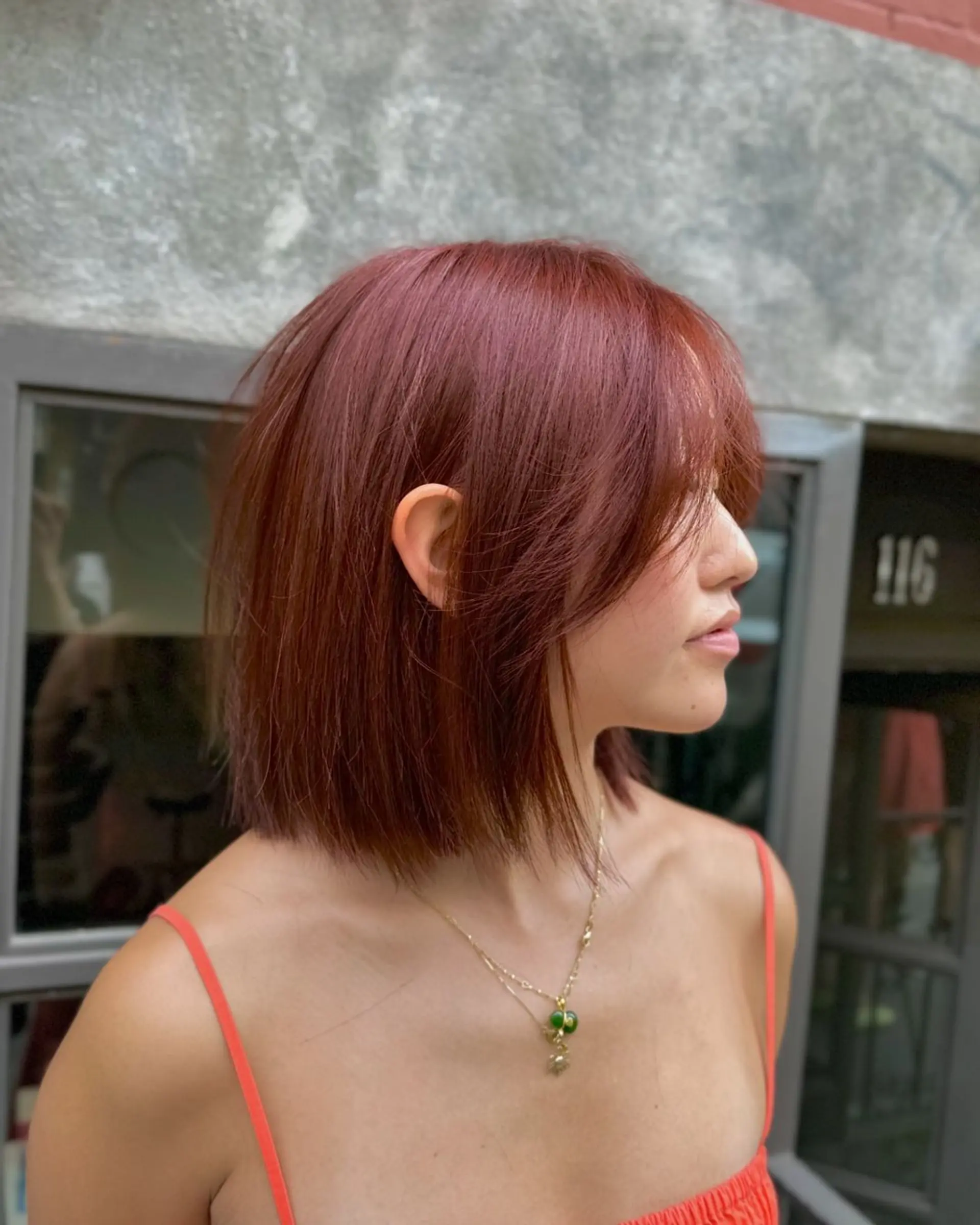 A vibrant red bob cut with a smooth, straight texture. Medium in length, featuring layered ends and side-swept bangs for added movement and volume. The hairstyle is single-toned in a beautiful crimson color. 3