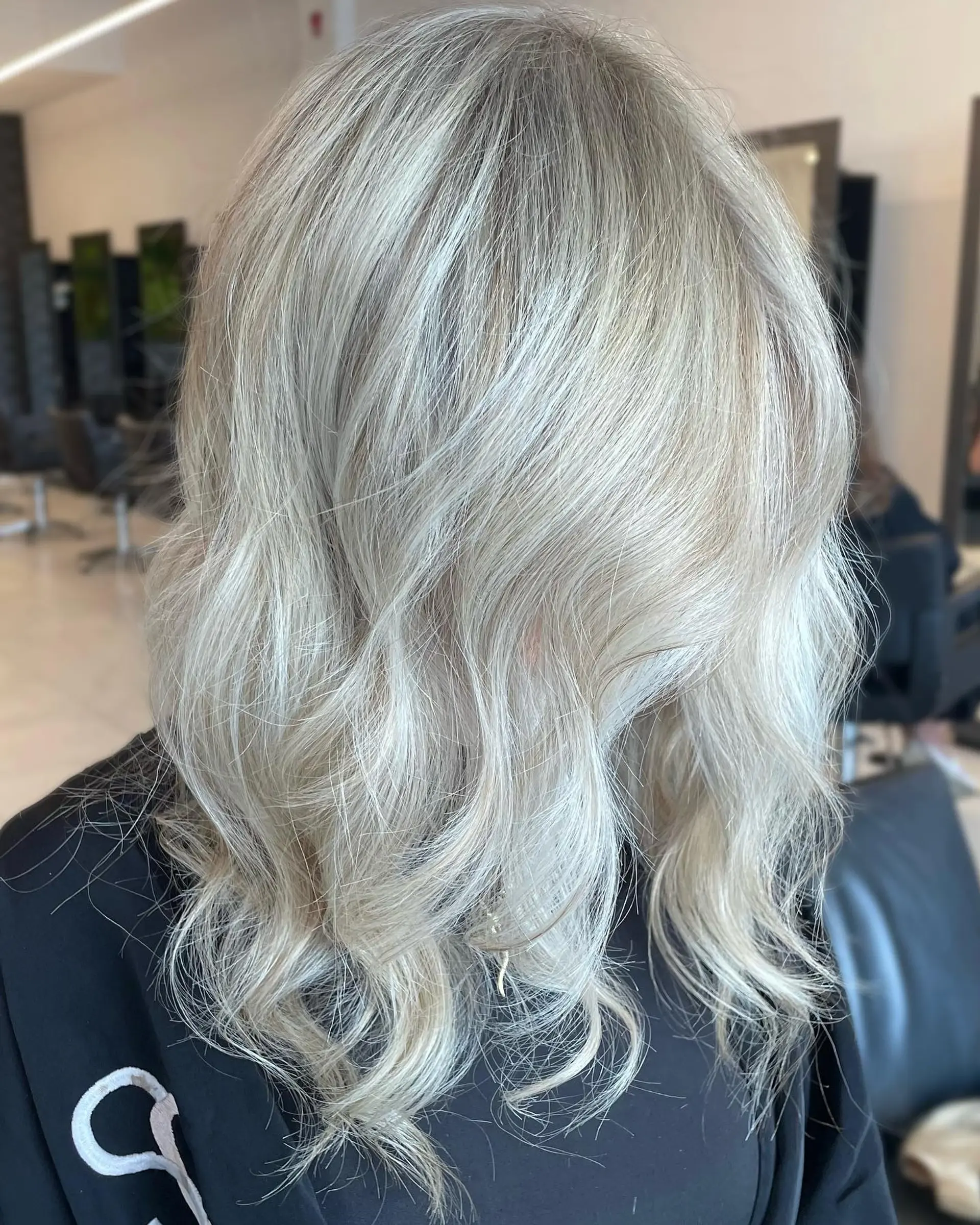 Medium-length icy platinum blonde hair styled with soft, loose waves and textured ends. 1