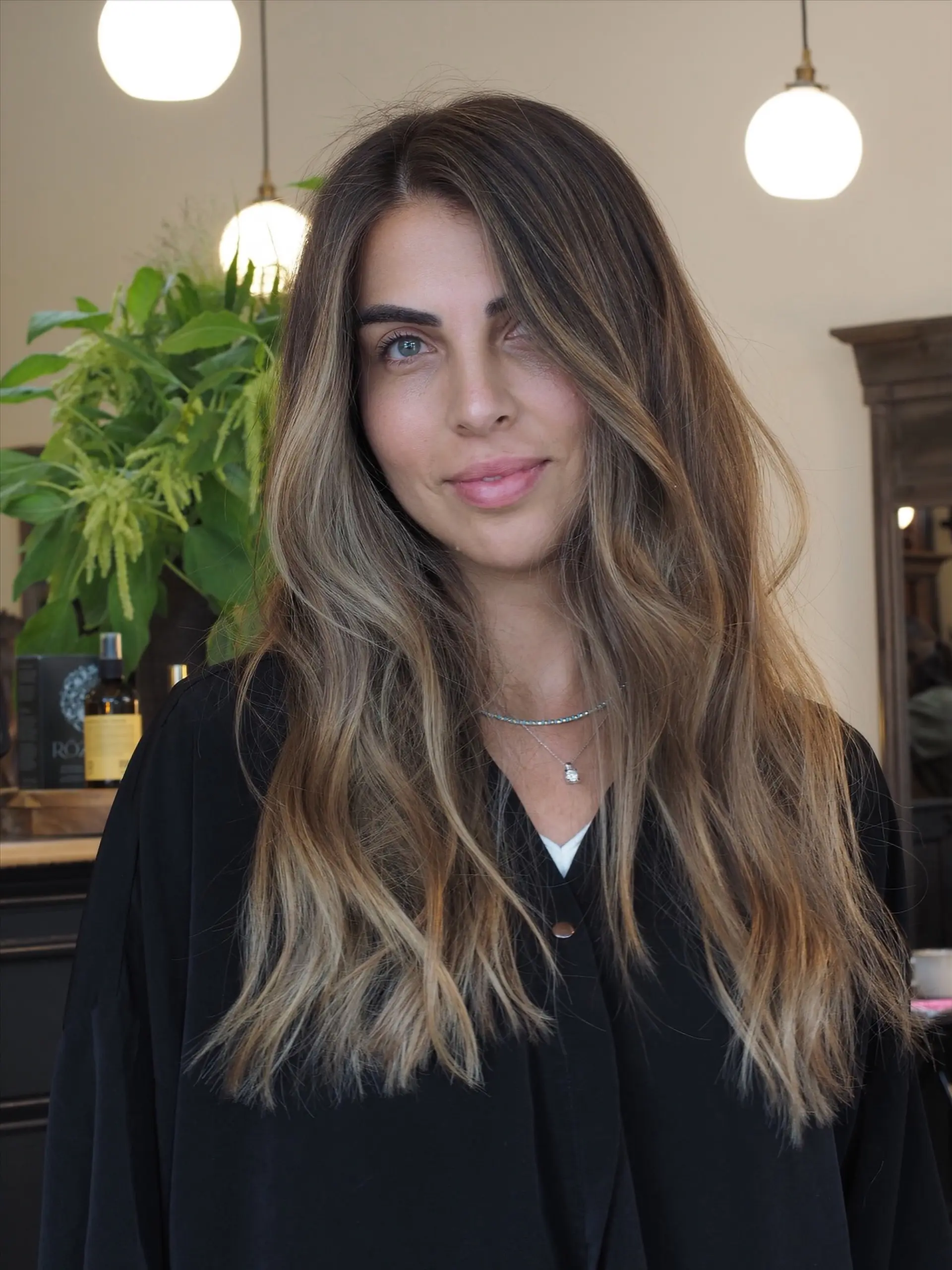 Long brunette hair enhanced with seamless, multidimensional ash blonde highlights styled in loose waves. 1