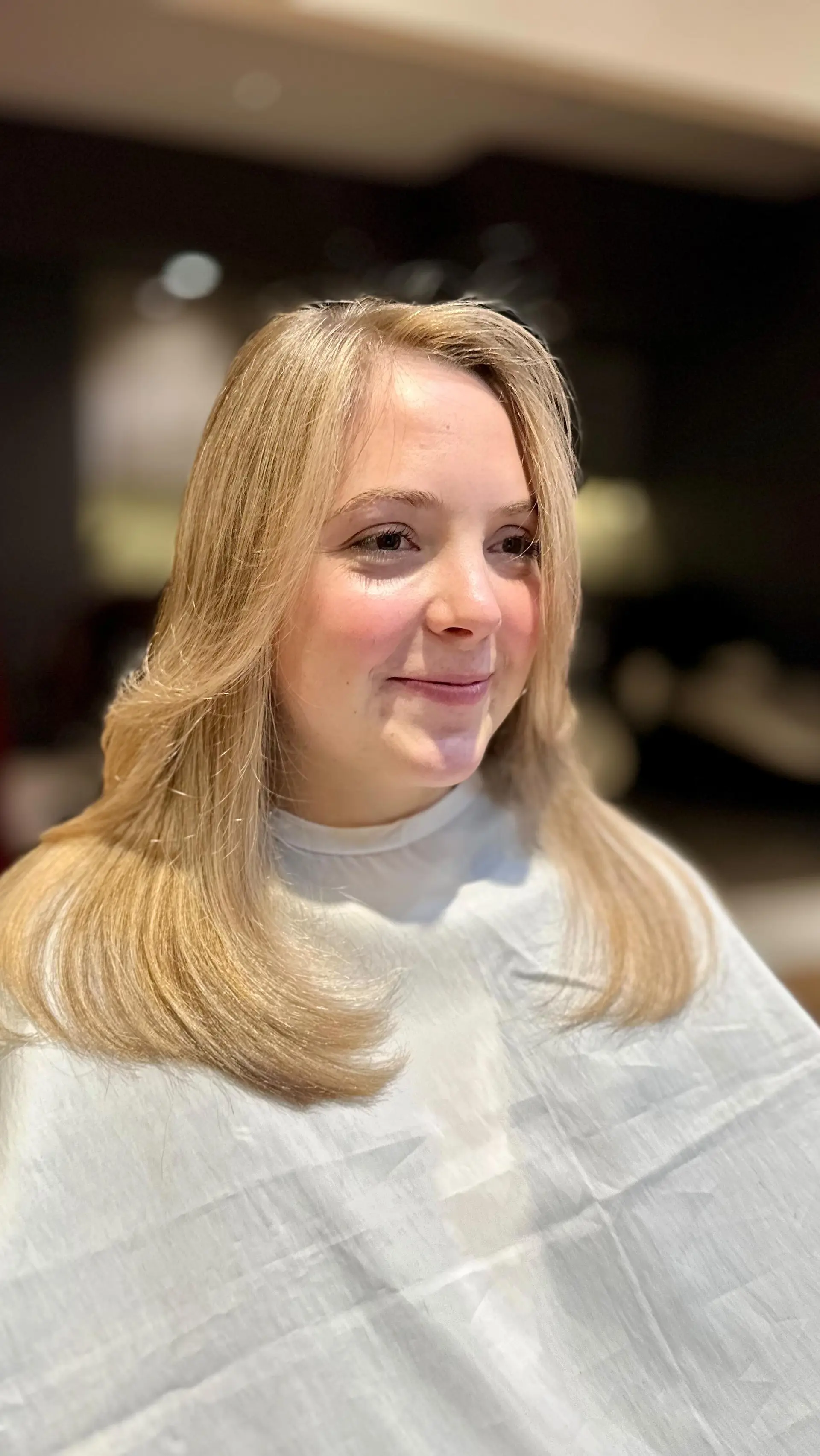 A medium-length golden blonde haircut styled in a smooth blowout with soft face-framing layers and flipped ends. 1