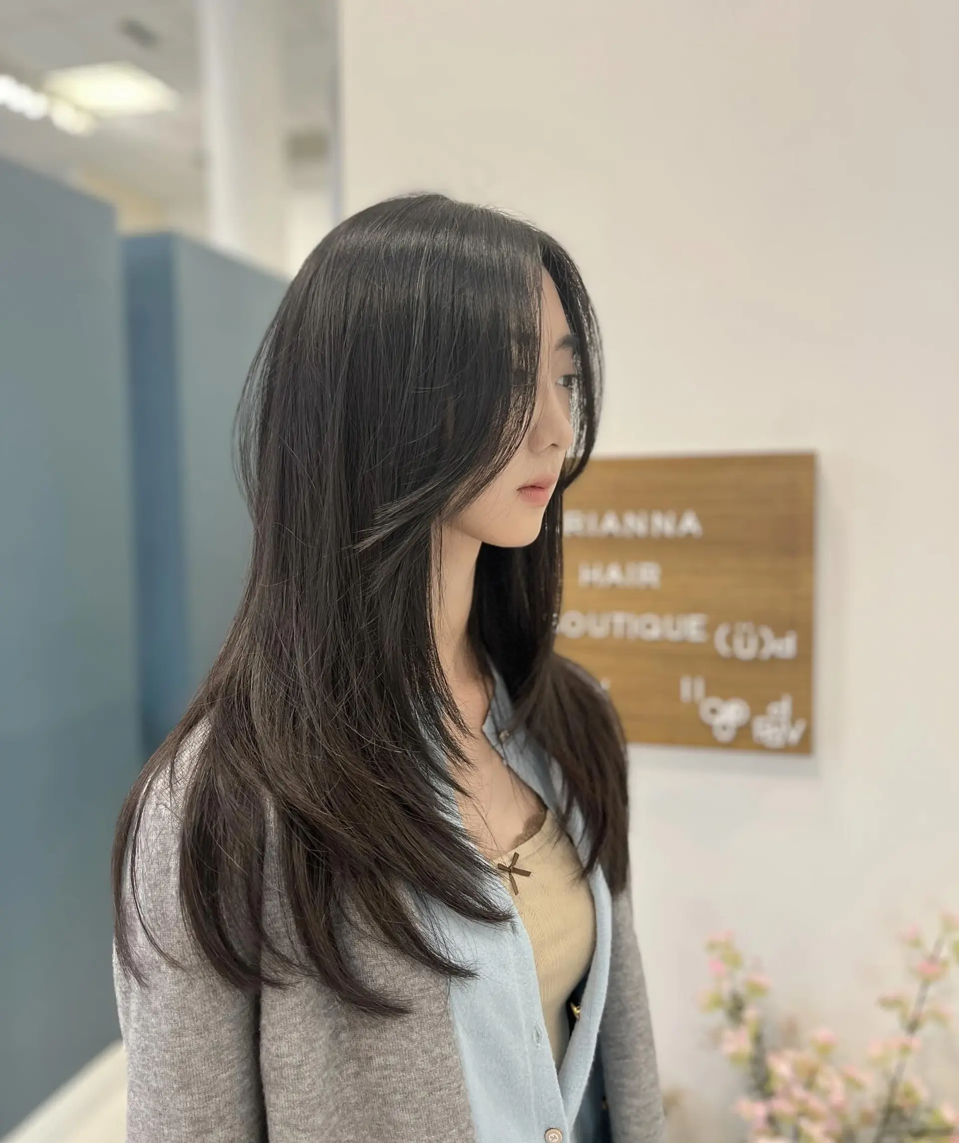 Long dark hair cut in soft flowing layers with face-framing curtain bangs styled with a gentle inward curve. 1