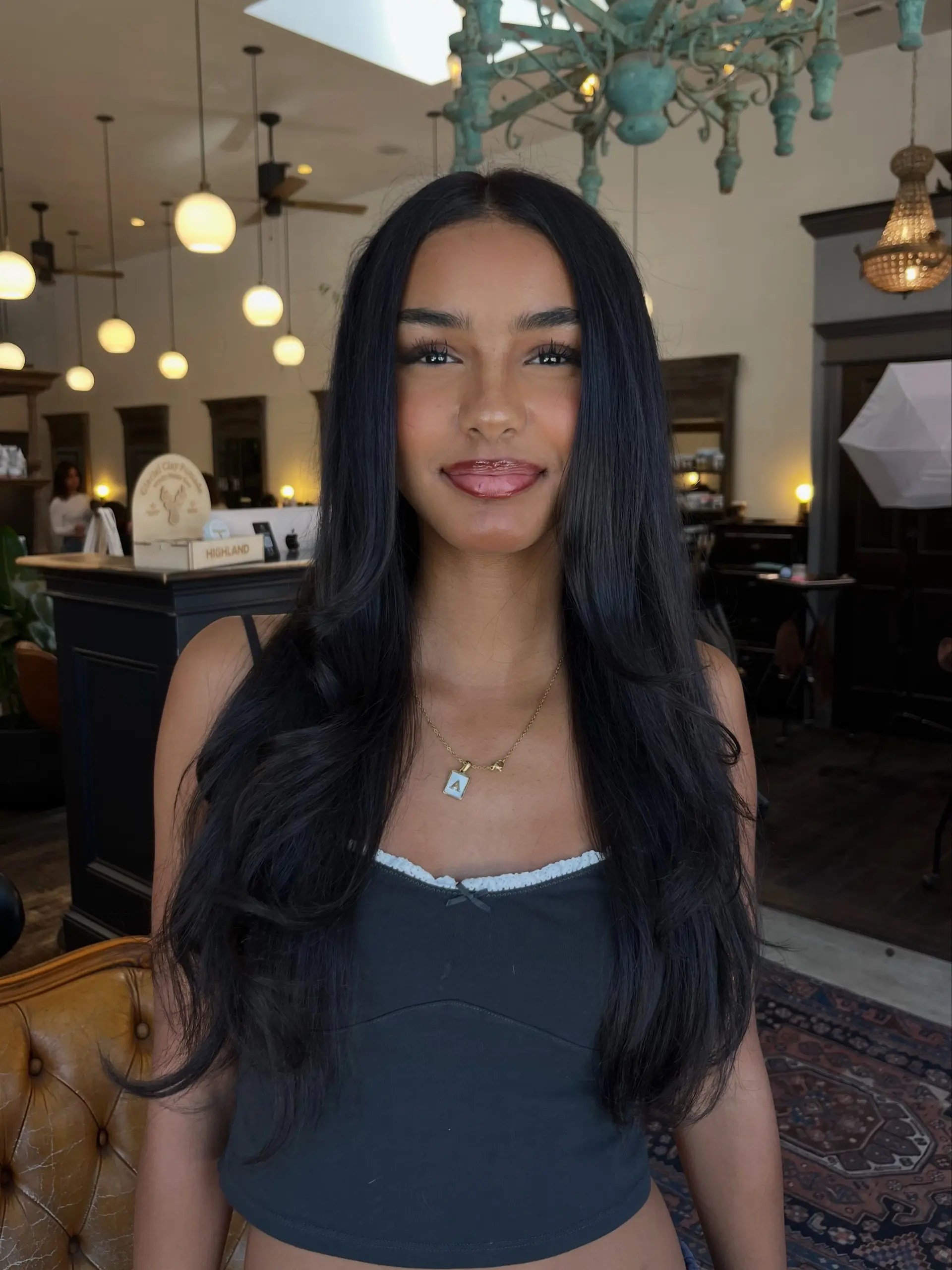 Long, rich jet black hair with face-framing layers styled in a voluminous blowout with soft curls at the ends. 1