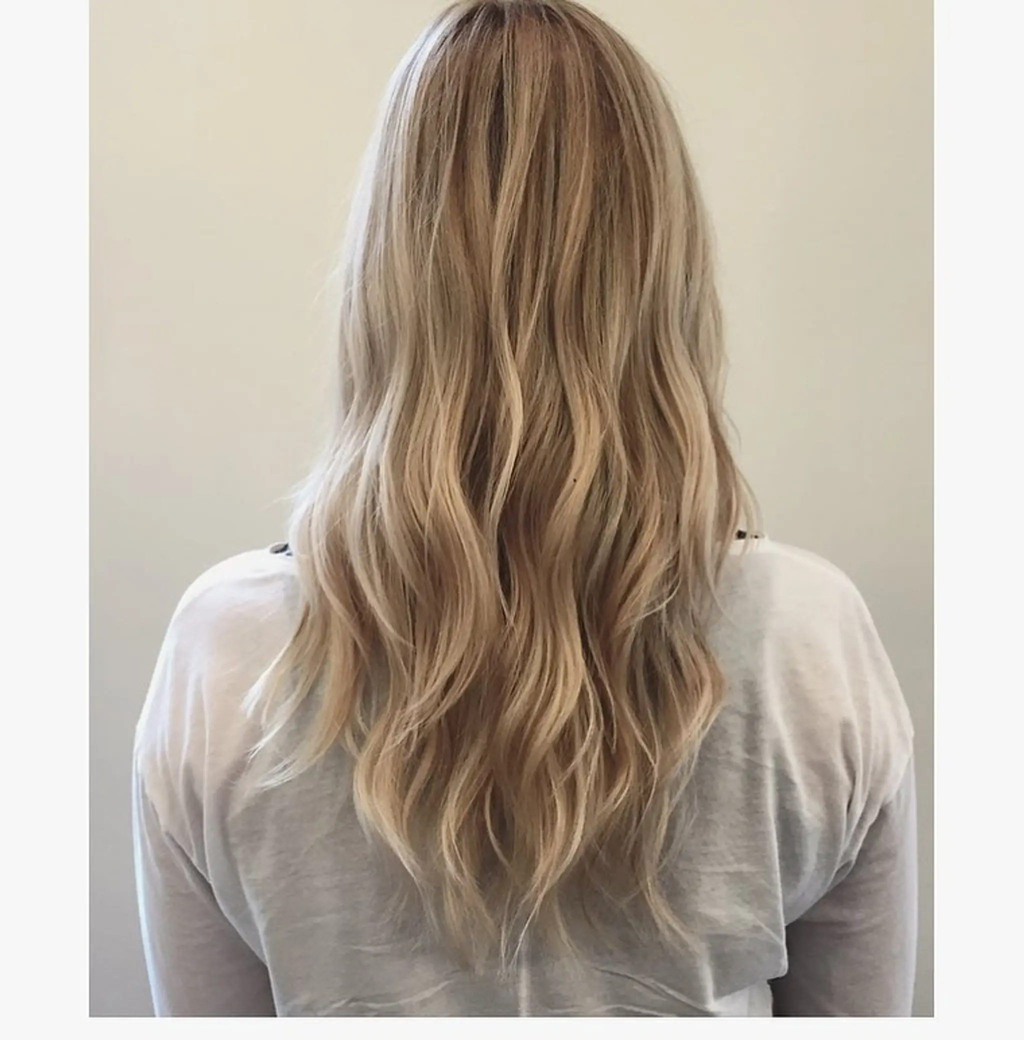 Long, flowing waves of sunlit blonde hair with subtle golden highlights. Loose, natural waves add volume and movement to the soft, wavy texture.