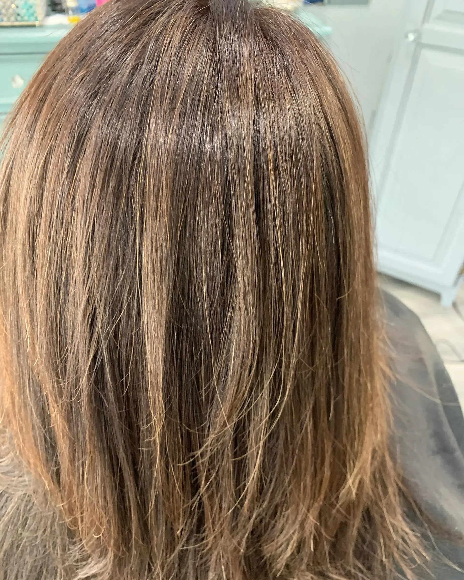 Straight, smooth blowout on medium-length layered brunette hair with subtle warm dimensional tones. 1