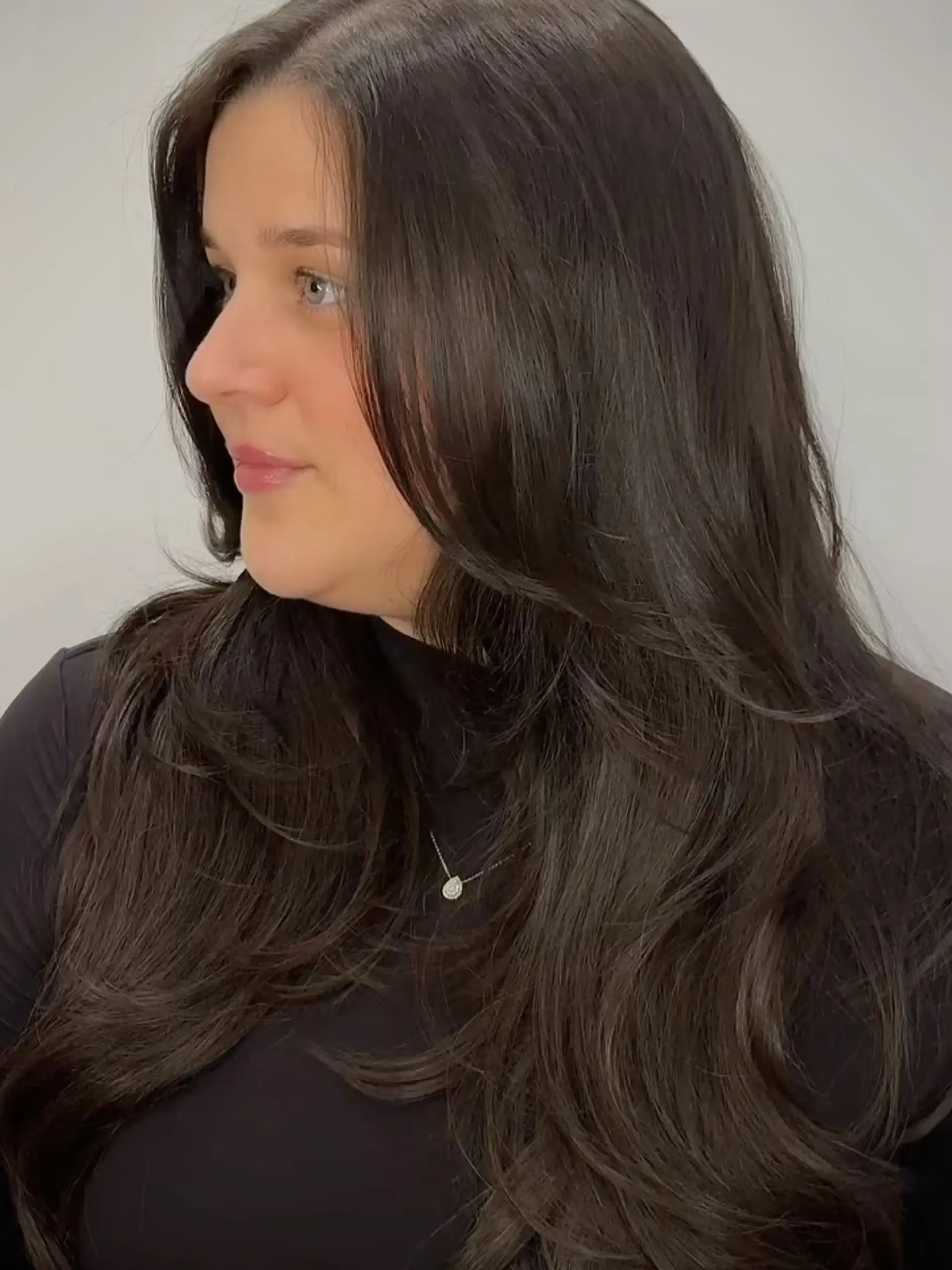 Voluminous long dark brown hair styled with soft, cascading layers and subtle face-framing curves. 1
