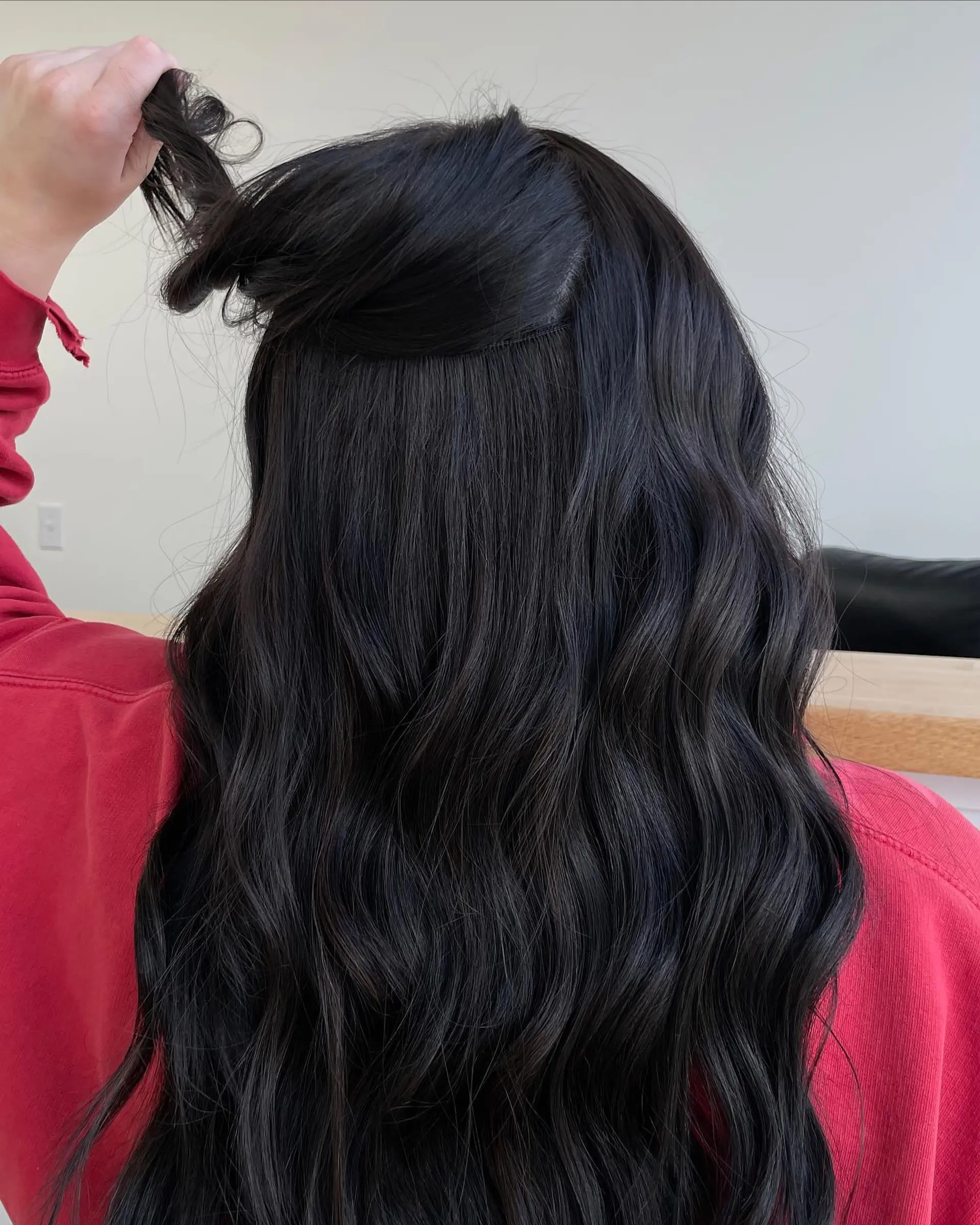 Long, dense dark hair styled in soft, flowing waves with seamless hand-tied extensions. 1