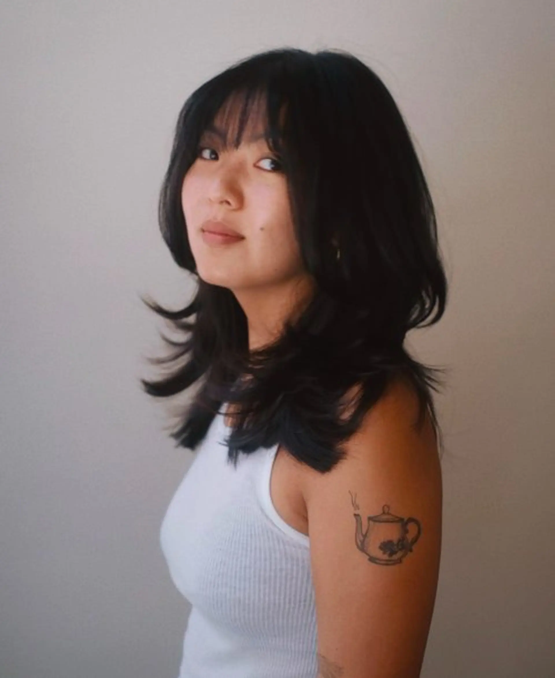 A medium-length layered bob with shaggy texture and curtain bangs. 1