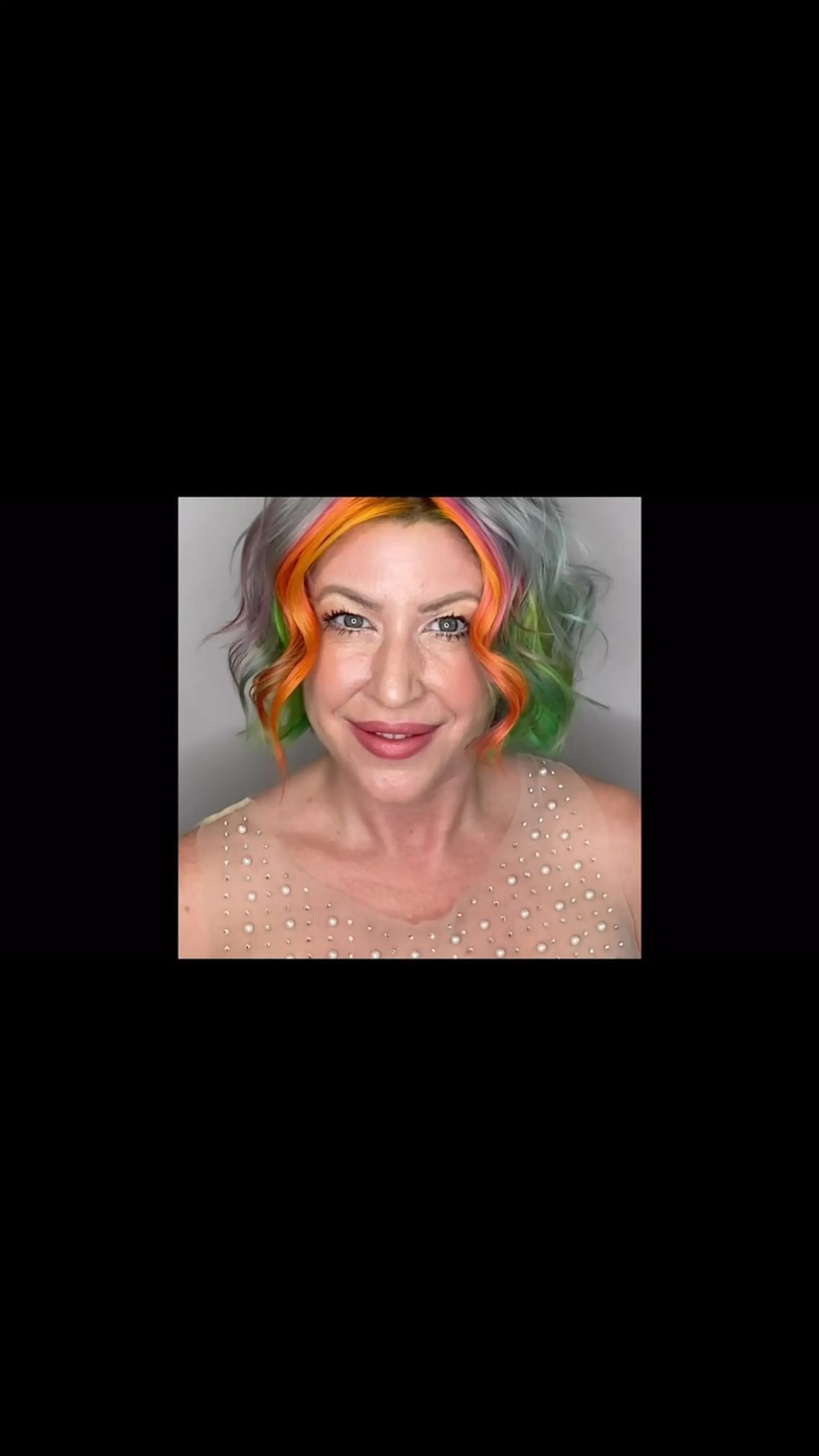A short, wavy bob featuring a vibrant multicolored money piece framing the face against cool silver and pastel tones. 1