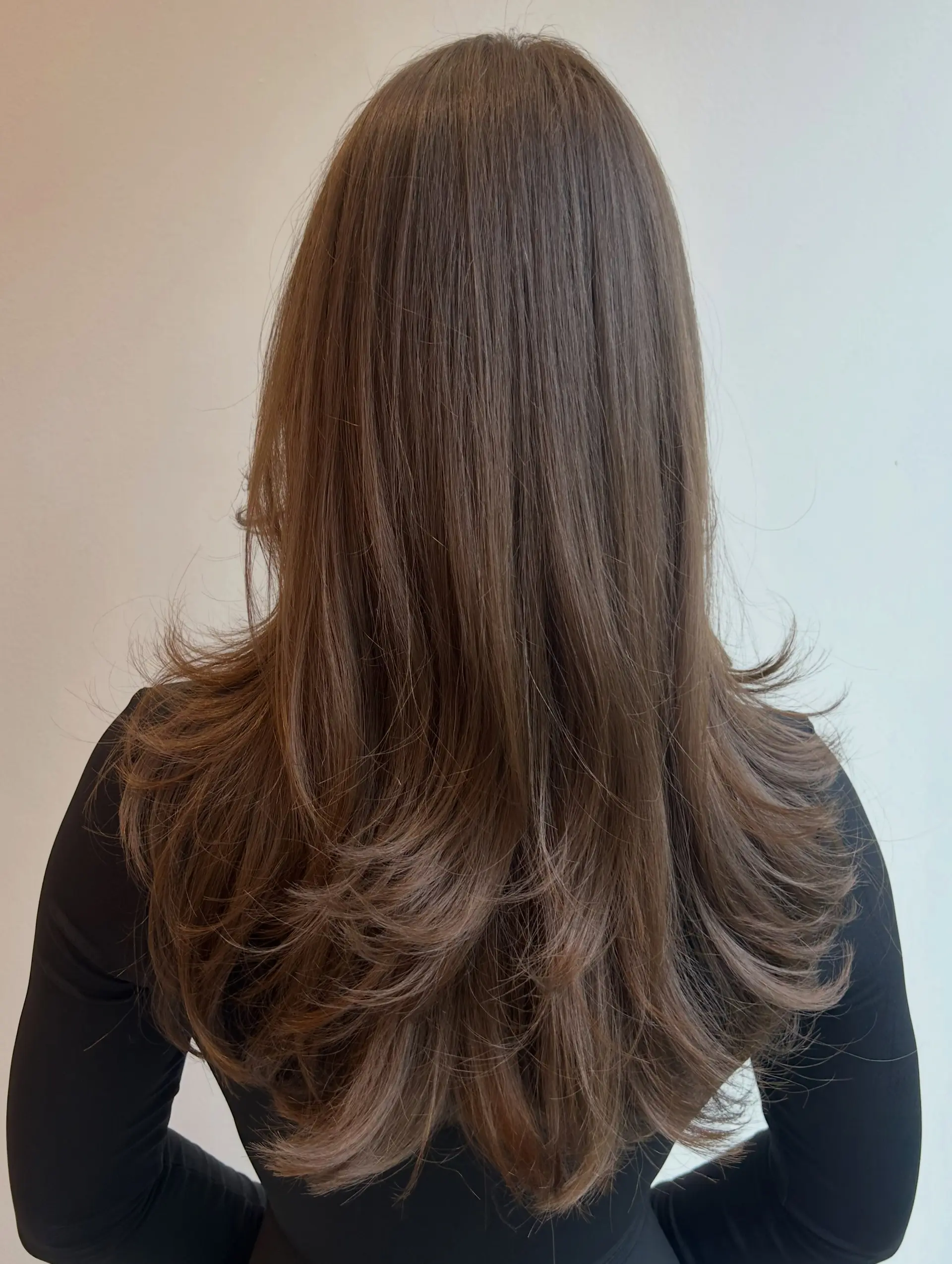 Long brown hair cut into cascading layers with feathered, flipped-out ends for volume and dimension. 1