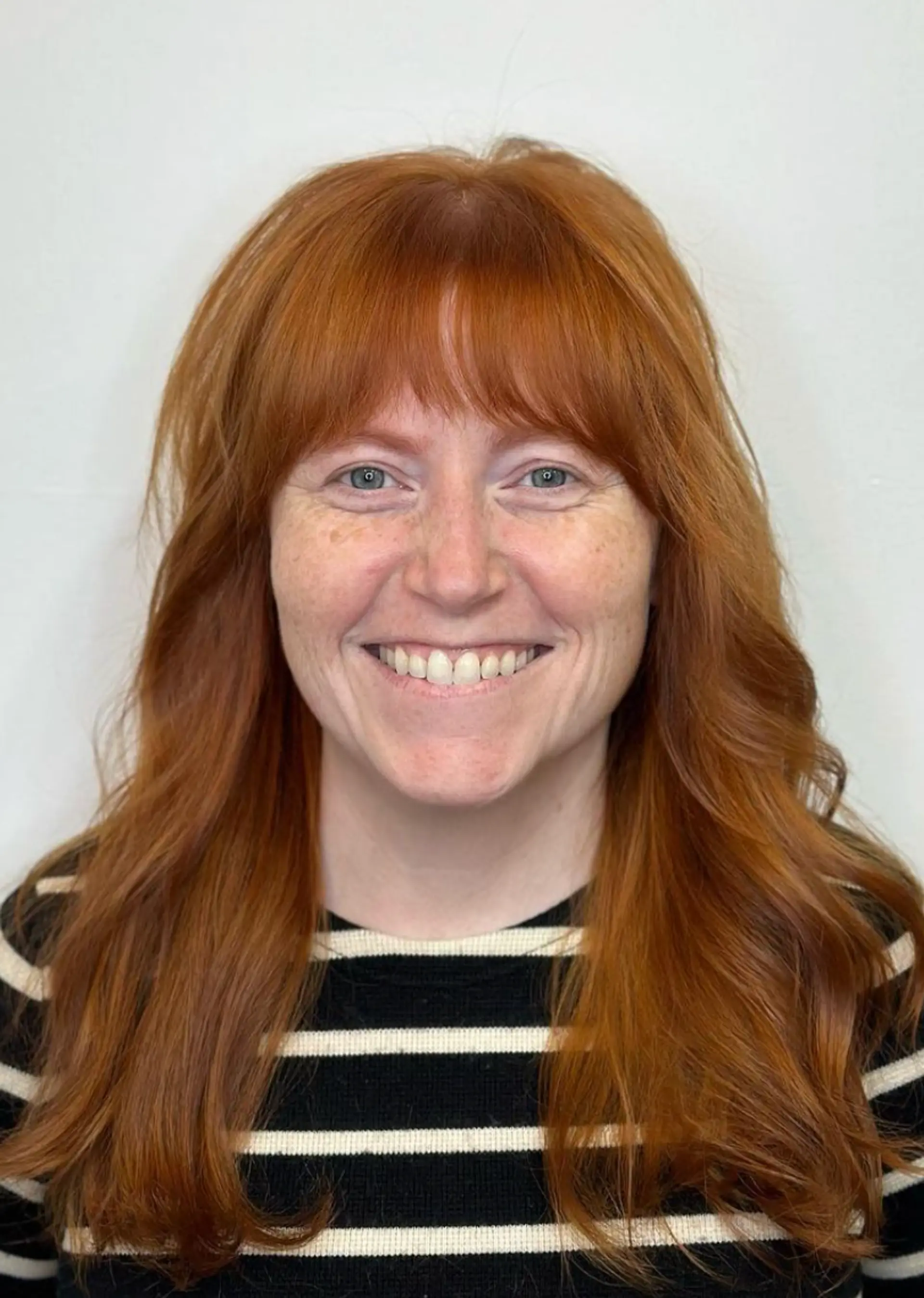 A rich auburn long hairstyle with natural wavy texture, featuring voluminous, layered waves and full bangs.

Color by @simabeautynyc 1