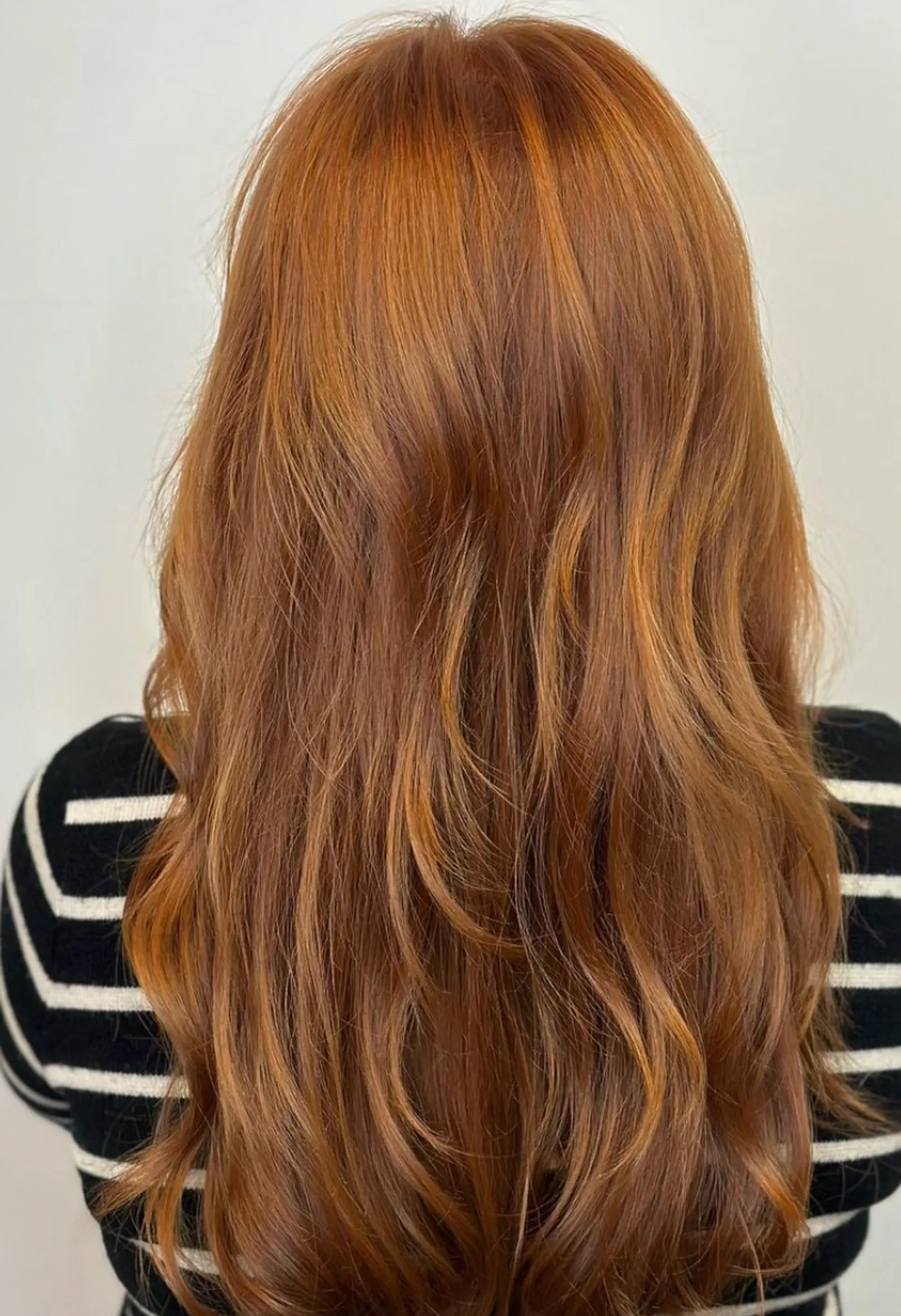 A rich auburn long hairstyle with natural wavy texture, featuring voluminous, layered waves and full bangs.

Color by @simabeautynyc 2