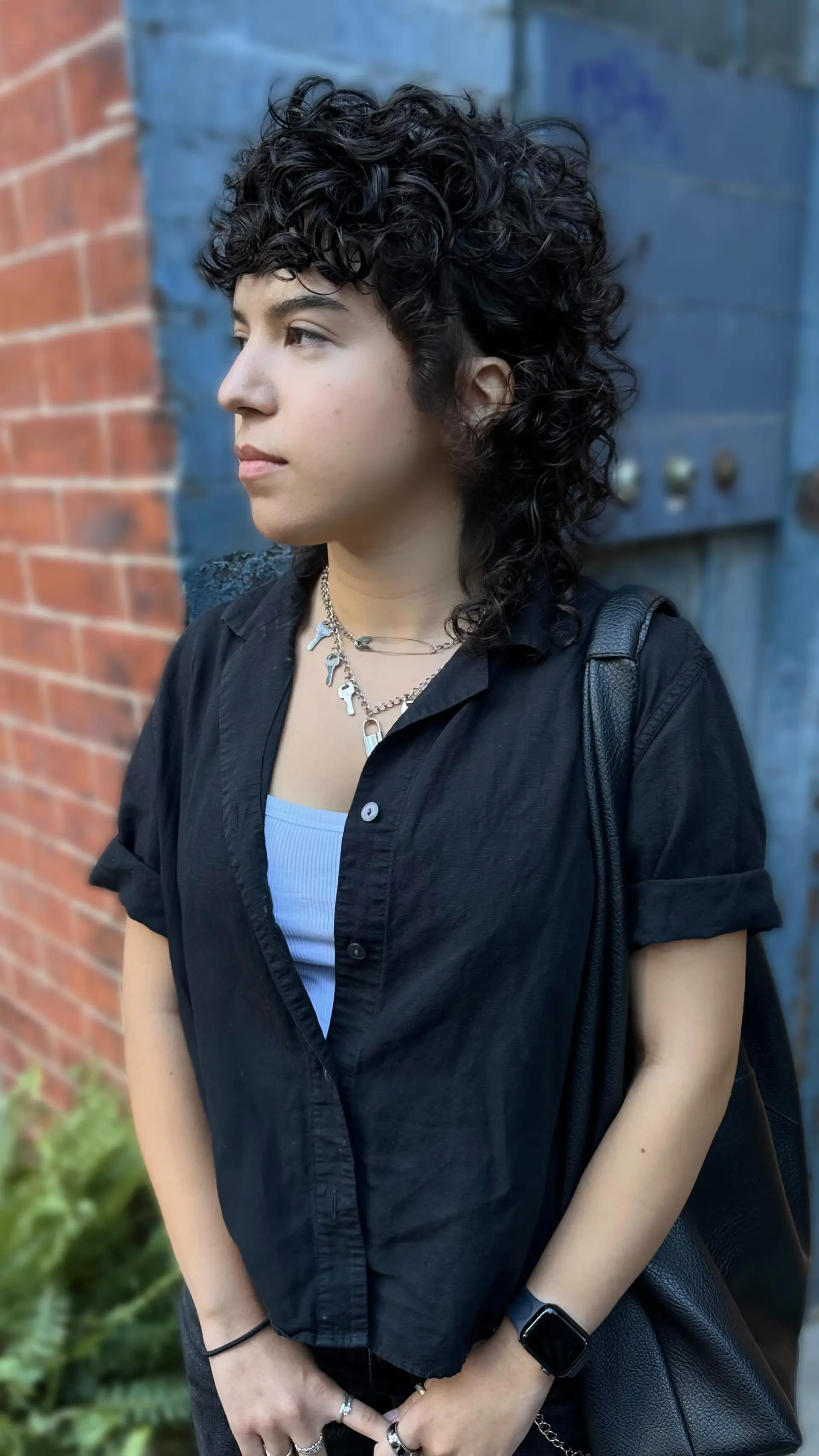 A dark, heavily layered curly mullet shag featuring textured curly fringe, defined coils, and length trailing softly at the nape. 1
