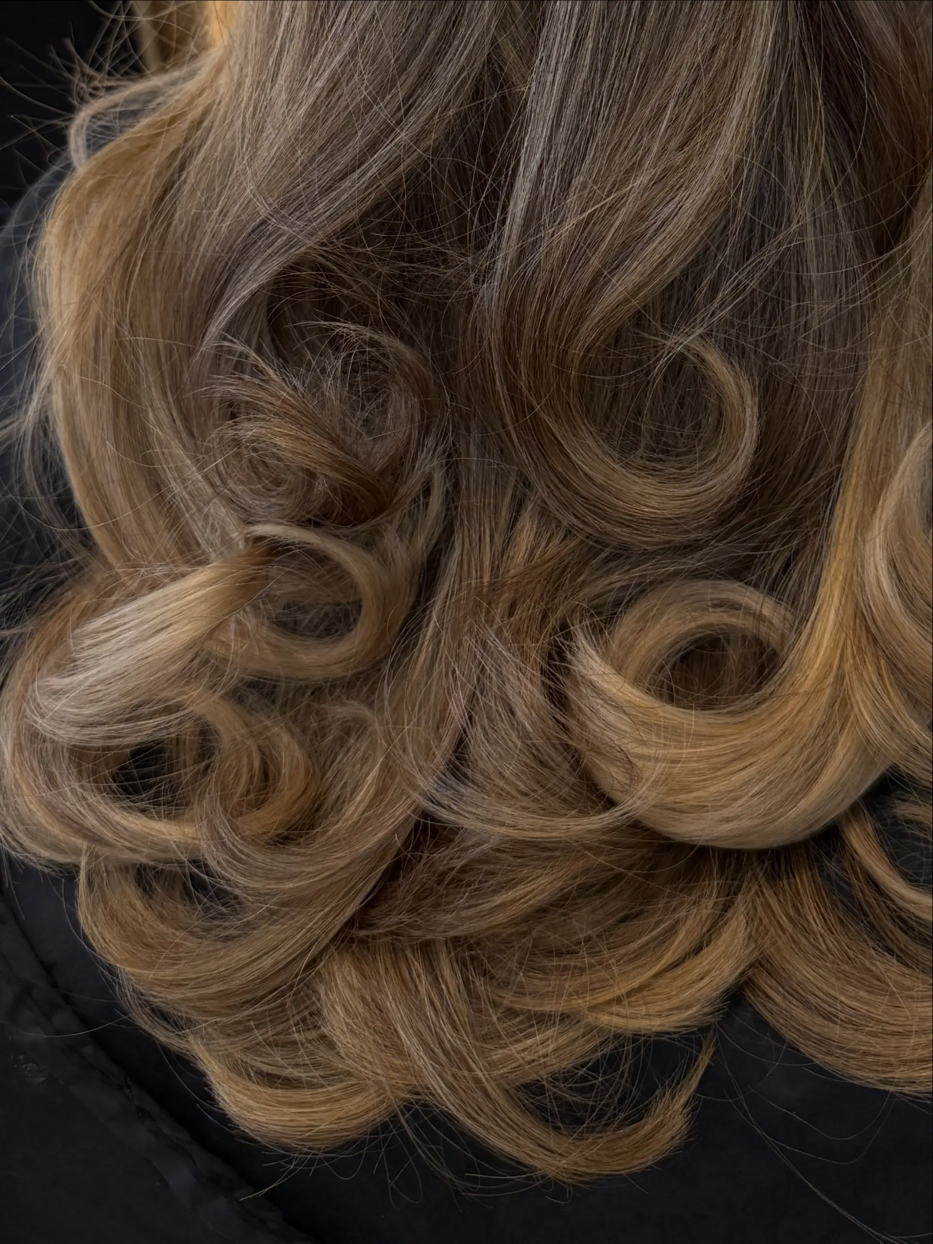 Dimensional bronde hair styled into voluminous, bouncy curls and rounded flipped ends. 1