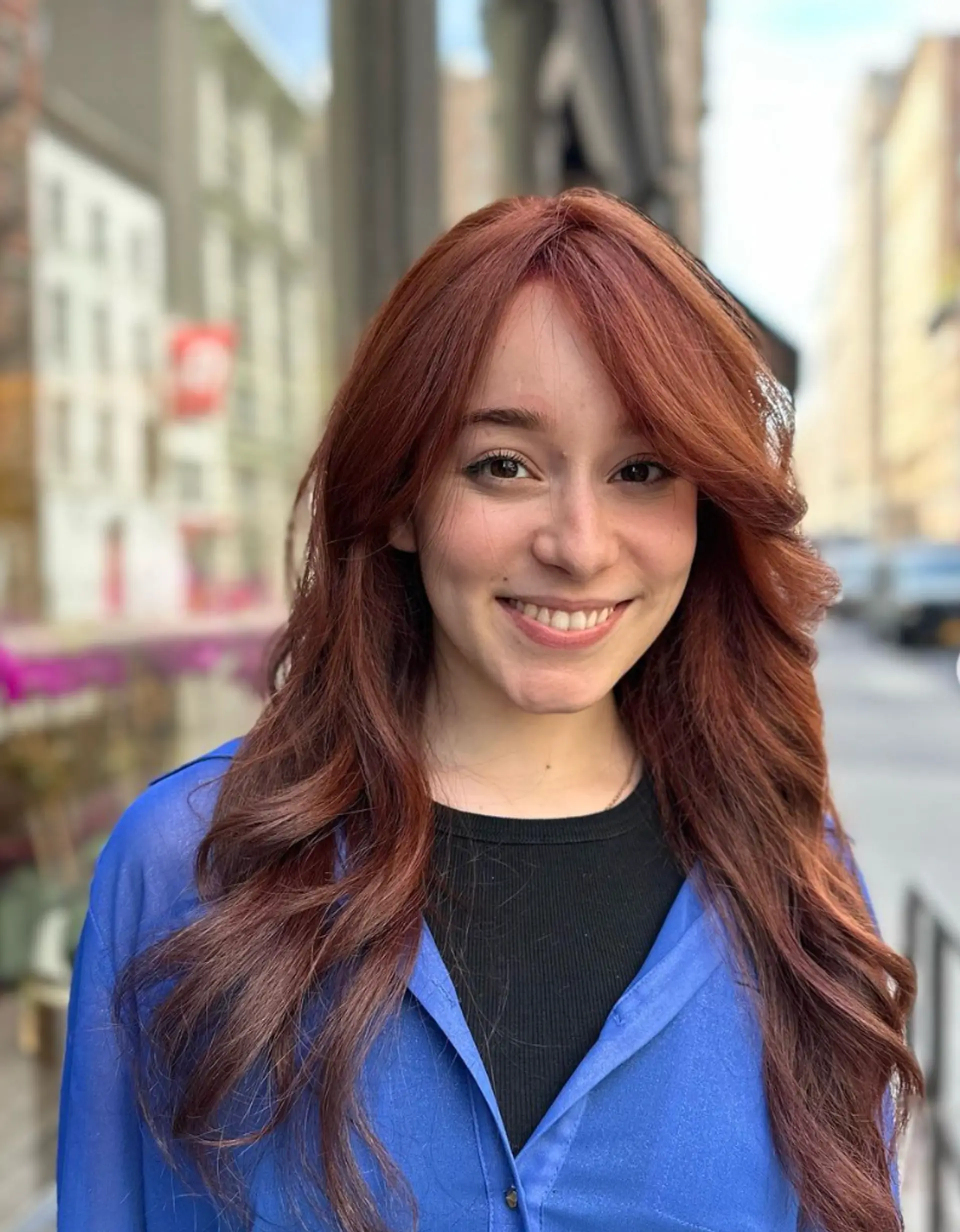 Long, wavy hair in a rich copper color with side-swept bangs and layered waves for added volume and movement. 1