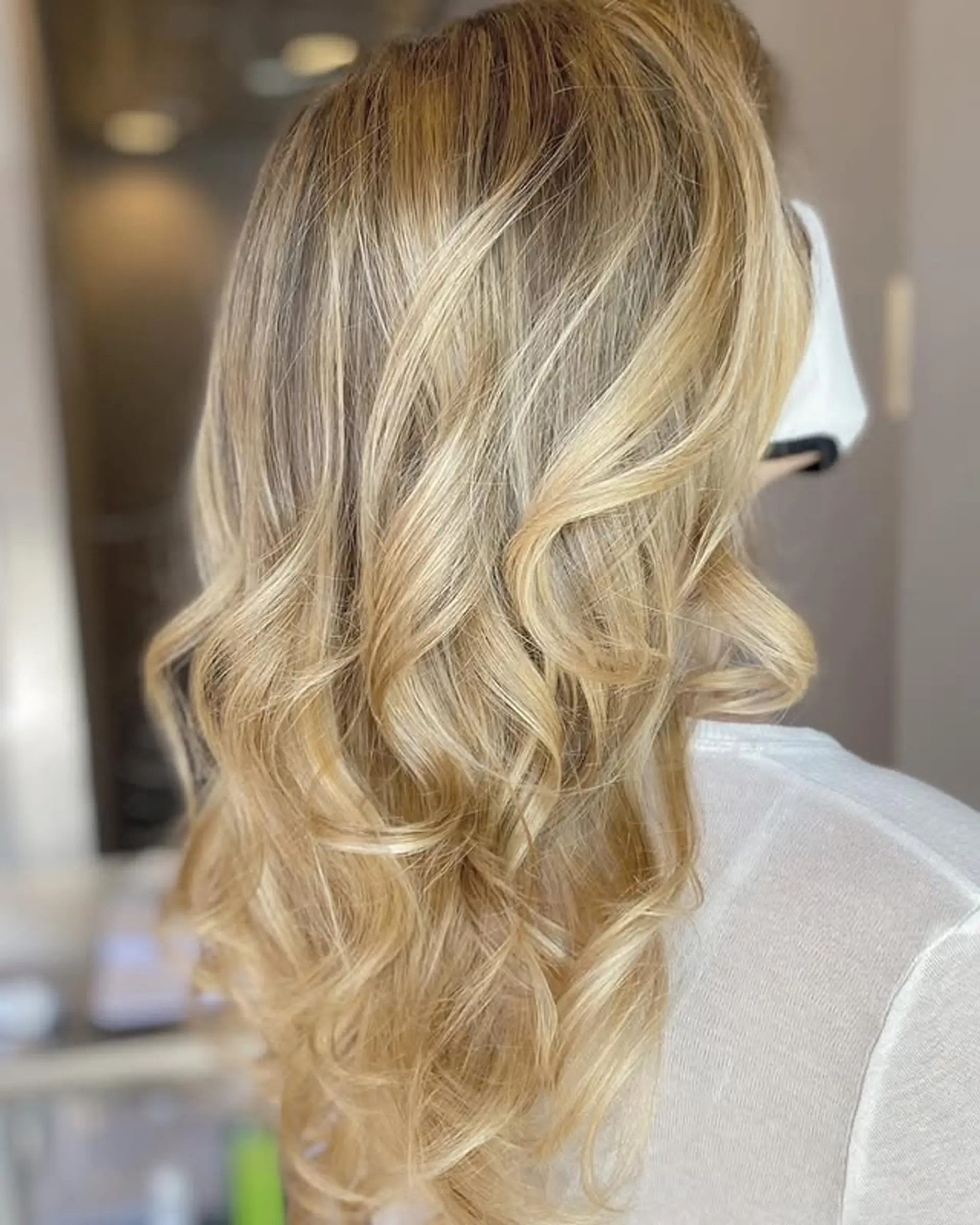 Long, layered wavy hair with a golden blonde balayage. 1