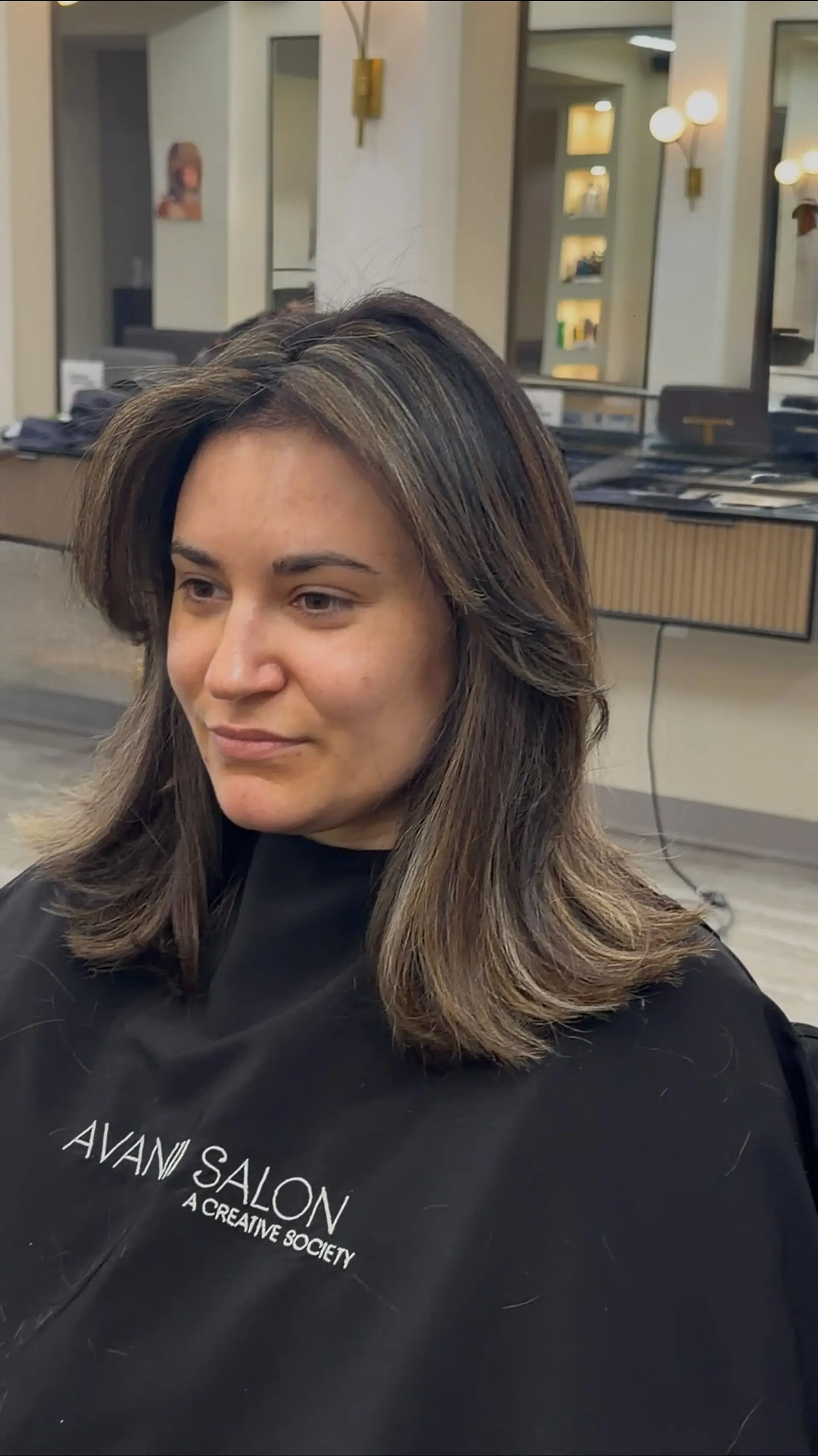Medium-length layered haircut with face-framing curtain layers and soft flipped ends, featuring subtle brunette balayage highlights. 1