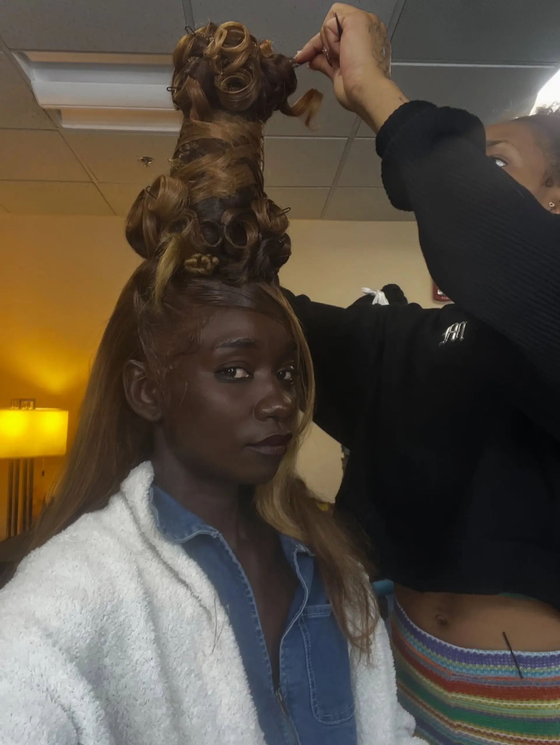 A dramatic, towering sculpted updo with stacked barrel curls and rolls, complemented by sleek swoop bangs. 1