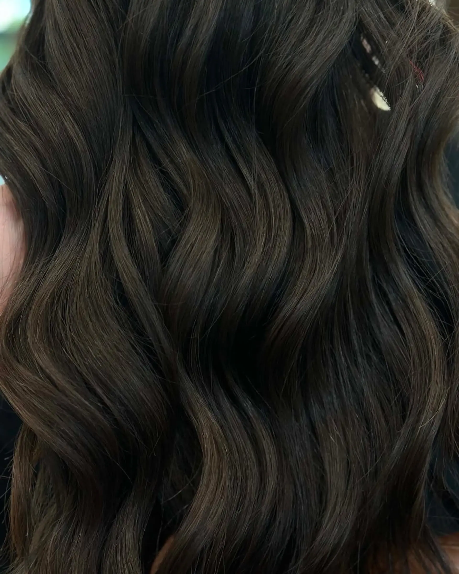 A close-up showcase of rich espresso brunette hair shaped with healthy ends and styled into soft, dimensional waves. 1