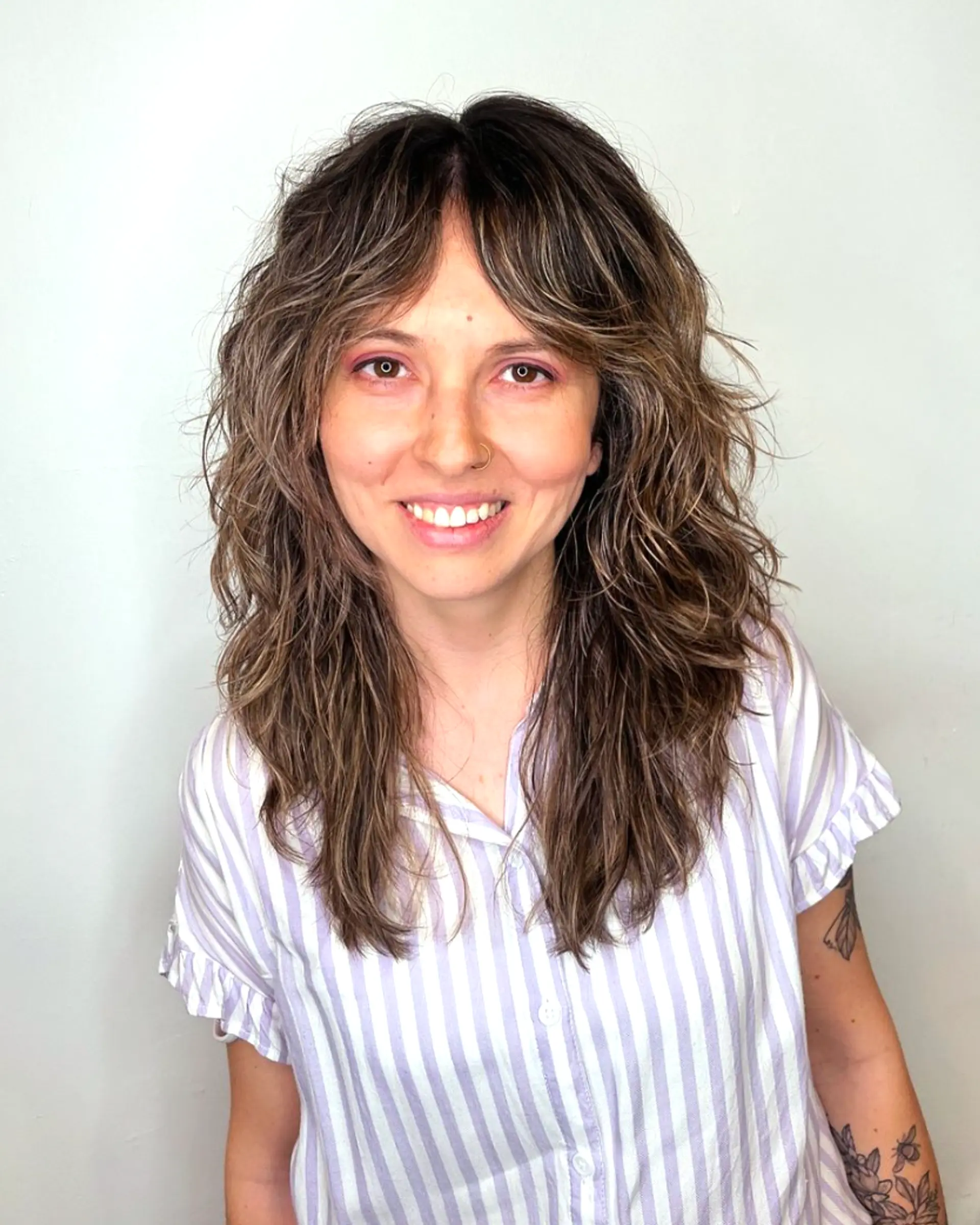 Long, wavy ash brown hair with natural highlights. Shaggy layers with a face-framing fringe and a tousled, messy texture.

Cut and style by @juliamannino_hair
Color by @simabeautynyc 1