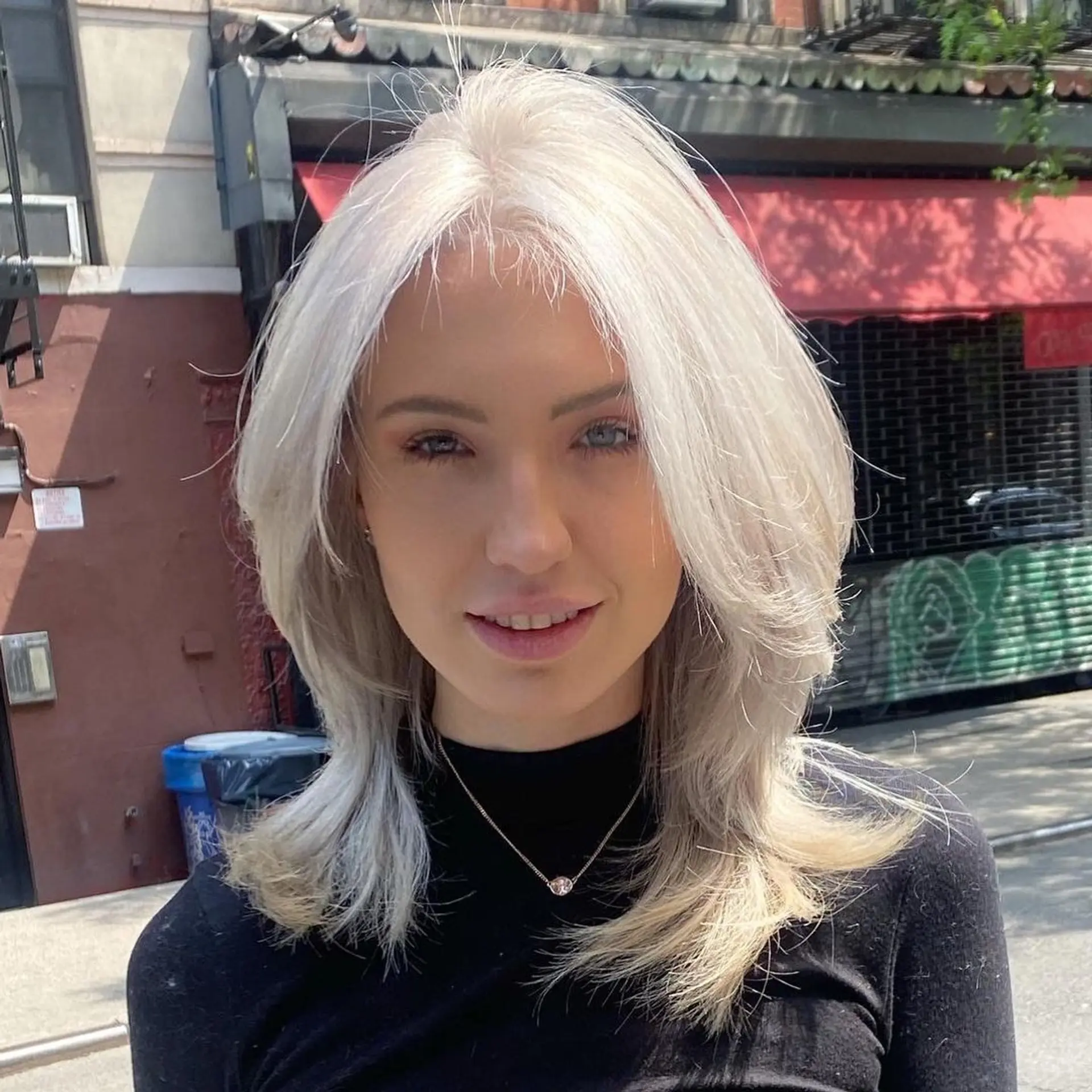 A stunning medium-length hairstyle with face-framing layers, feathered ends, a middle part, and a captivating silver-platinum shade. 1