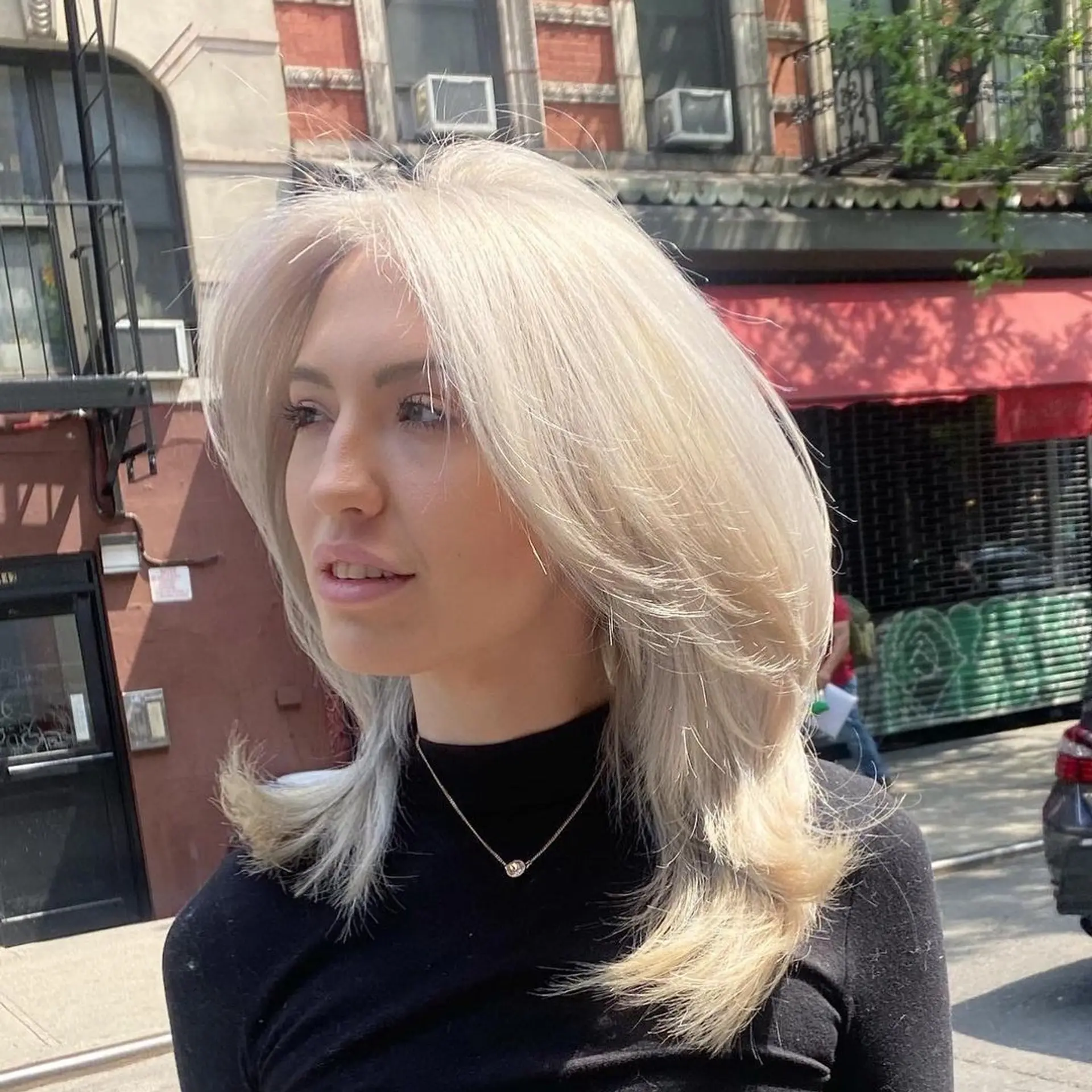 A stunning medium-length hairstyle with face-framing layers, feathered ends, a middle part, and a captivating silver-platinum shade. 2