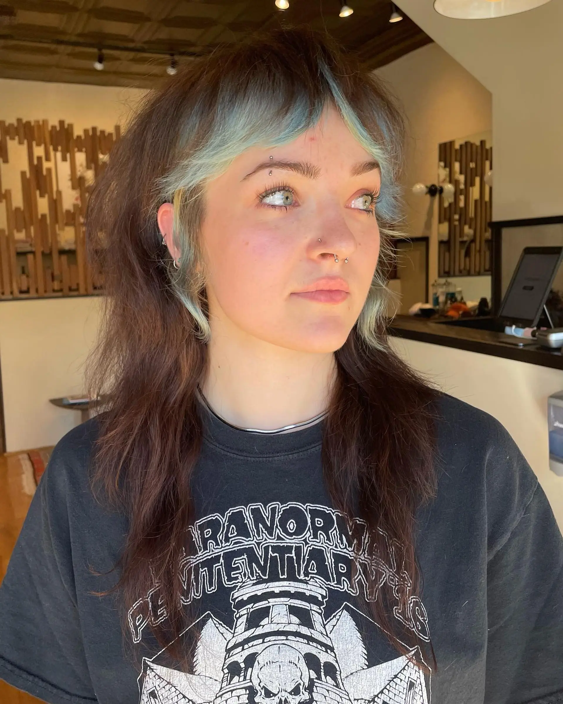 A modern take on the classic mullet, featuring layered, face-framing teal and blonde highlights. 1