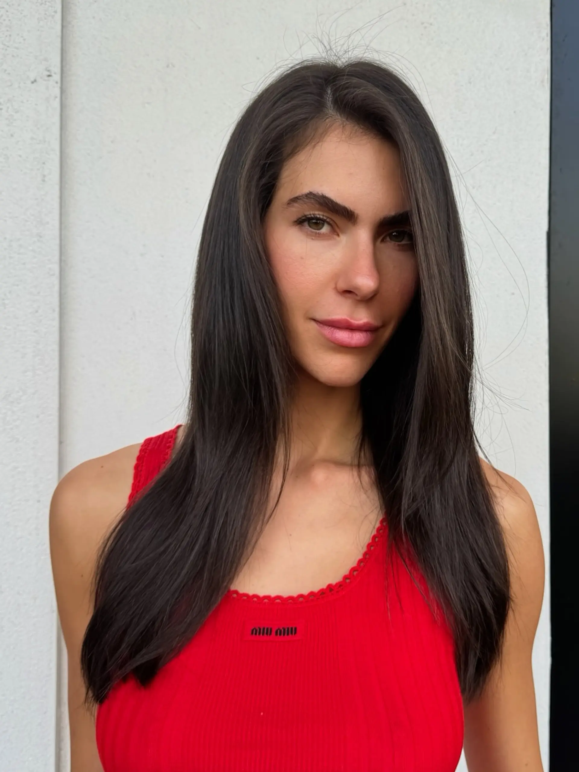 Long, ultra-smooth, dark brunette hair styled straight with high shine and a natural center-parted drape over both shoulders. 1