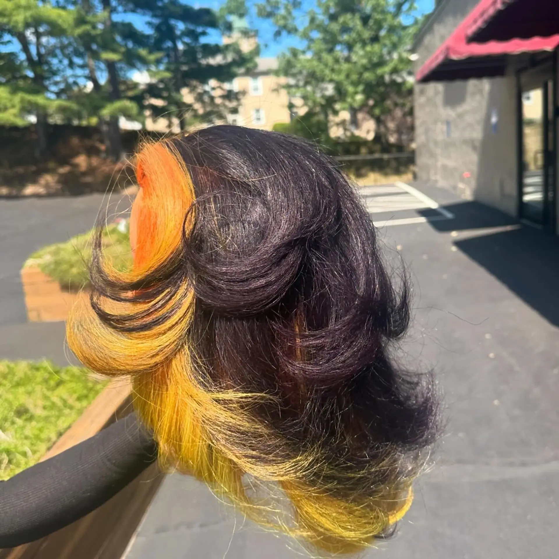 Layered mid-length blowout showcasing a vivid orange and yellow halo color melt underneath dark violet-black flipped layers. 1