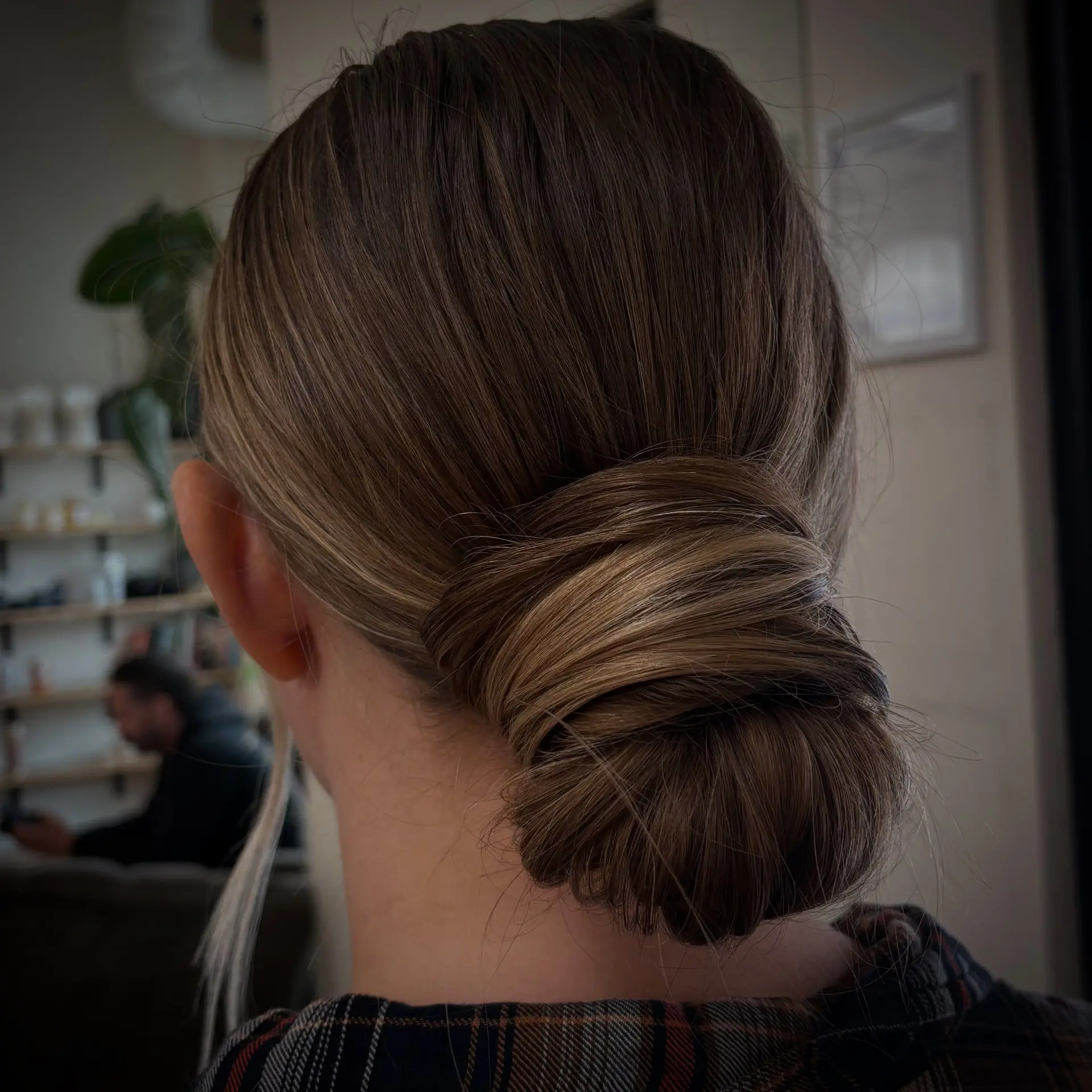 A polished low chignon wrapped neatly at the nape of the neck. 1