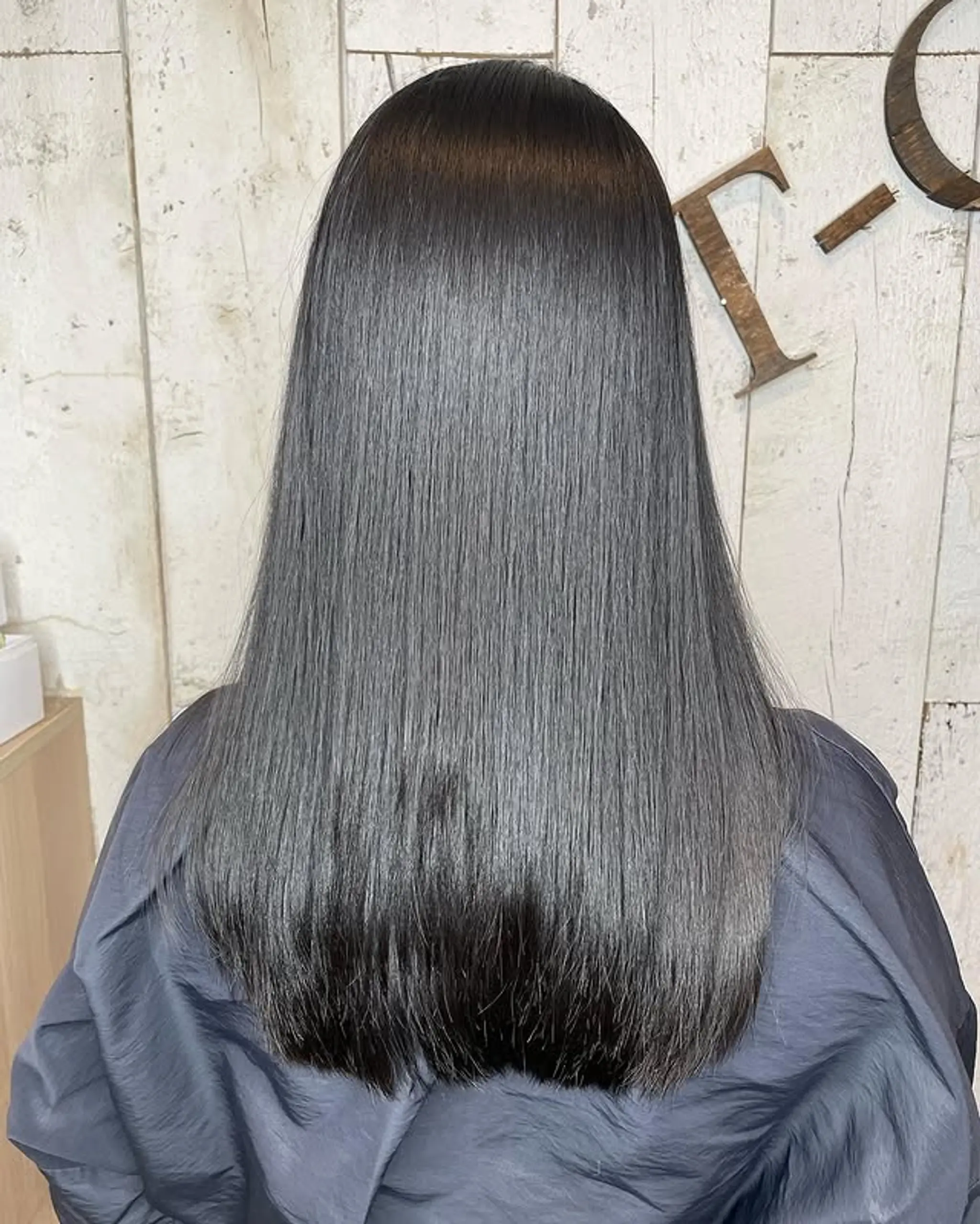 A long, straight hairstyle with a dark to steel gray/silver ombre.