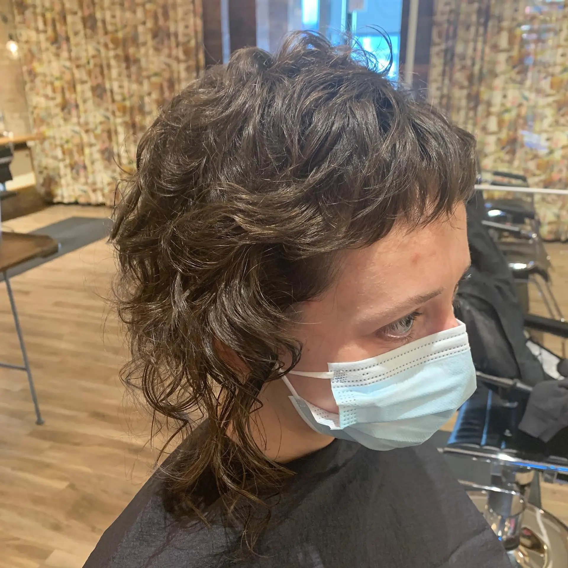 A short, textured pixie cut with fantasy color accents of green and purple. 2