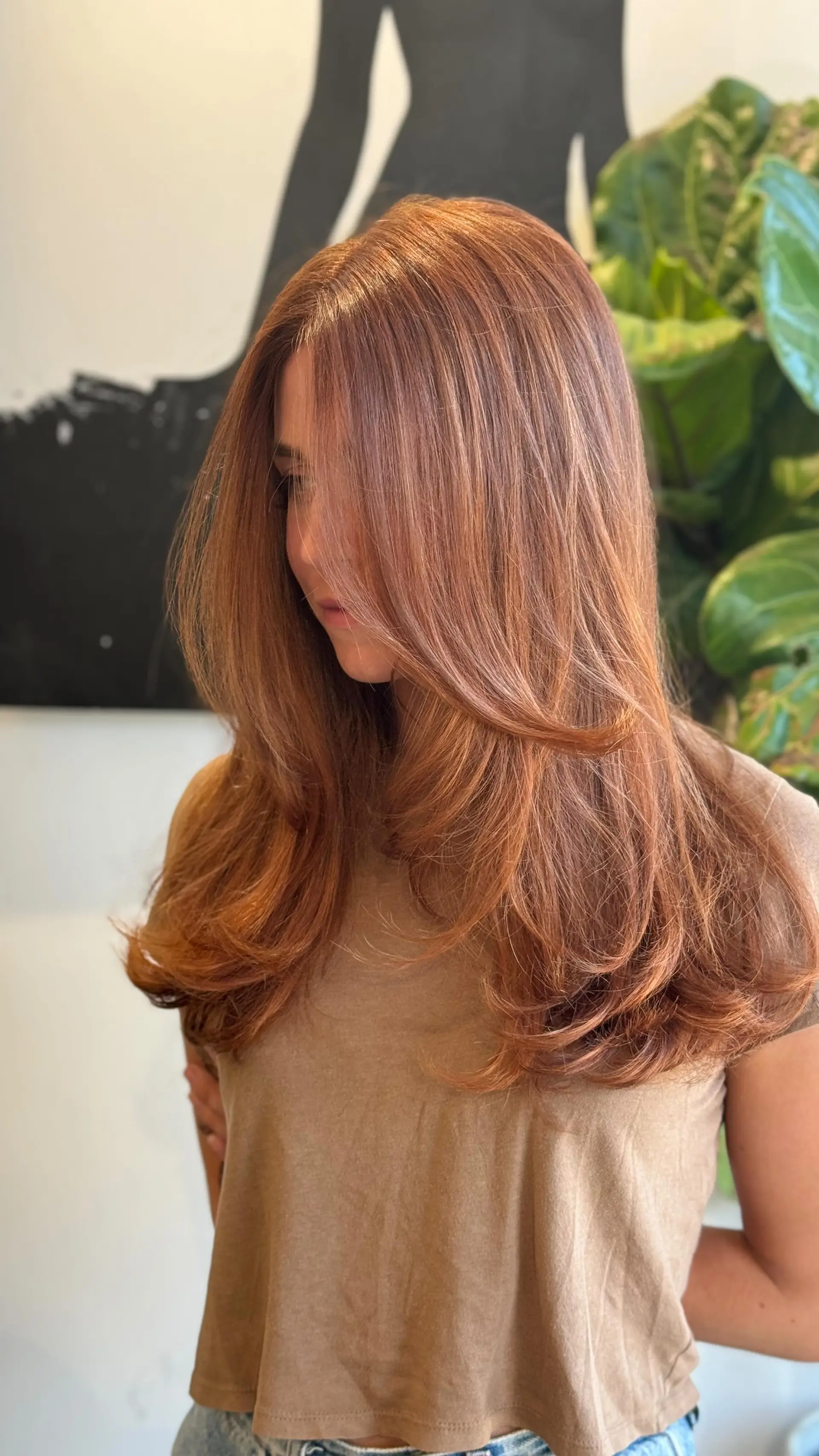 A long, layered haircut styled into a bouncy blowout with curled ends and face-framing layers in a radiant cowboy copper tone. 1