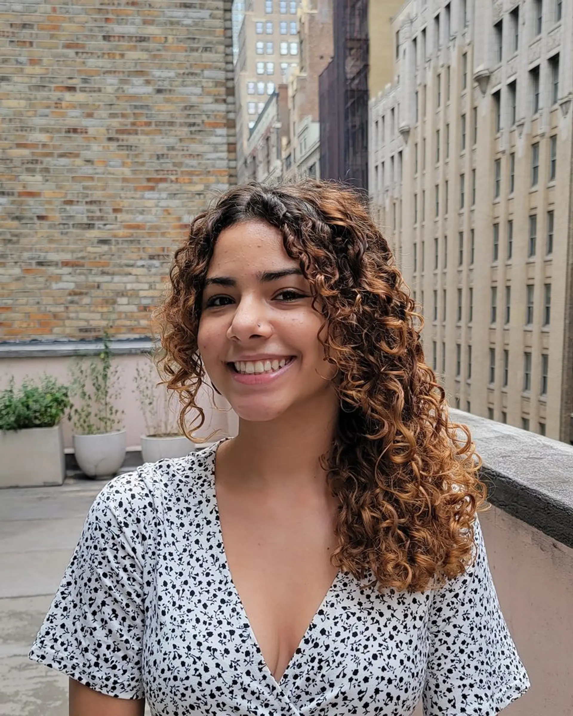 A captivating curly hairstyle with medium-length brown hair cascading naturally with a subtle side part, enhancing the texture and volume. 1