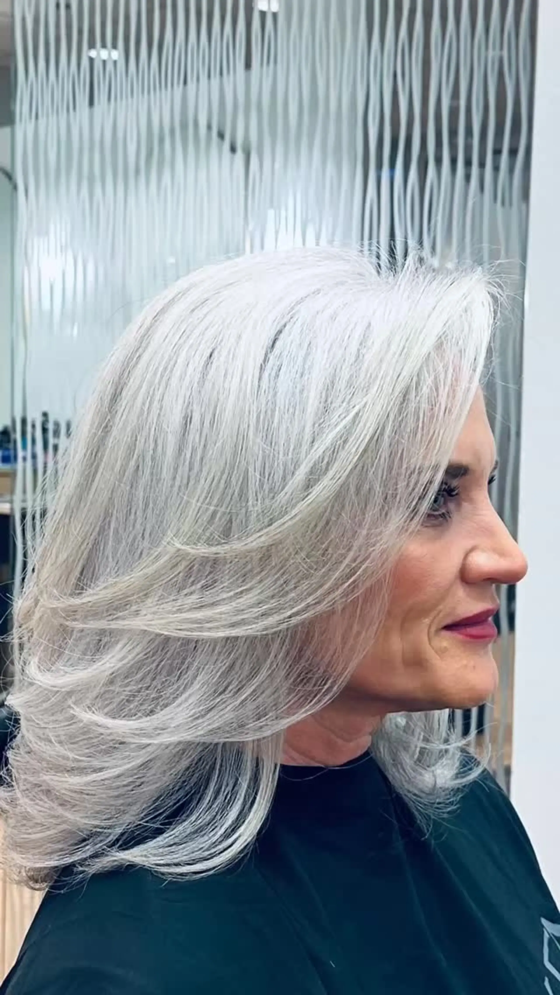 Medium-length silver hair styled into face-framing, feathered layers with a classic voluminous round-brush blowout. 1