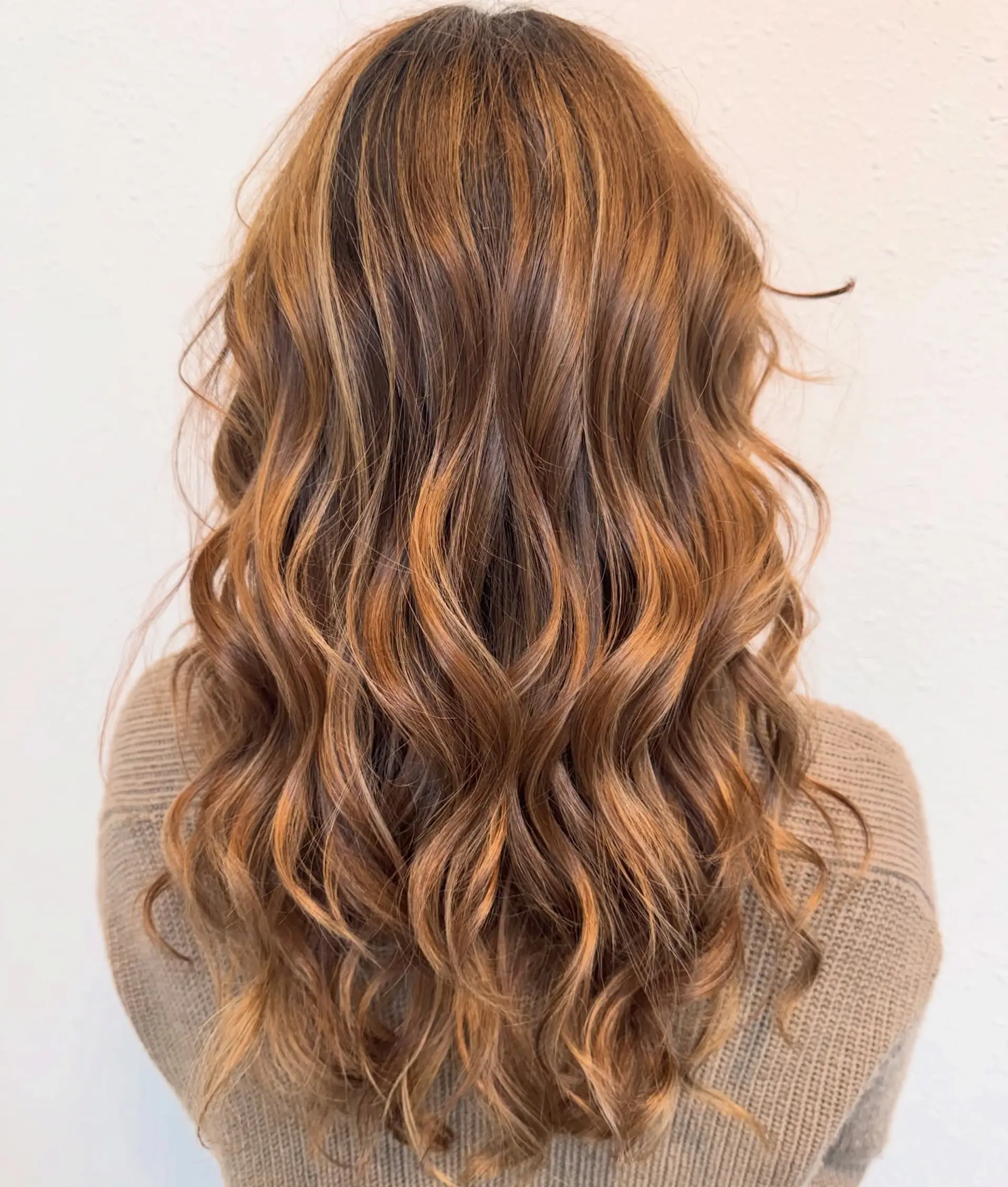 Long warm brunette hair with dimensional caramel balayage styled in loose flowing waves. 1